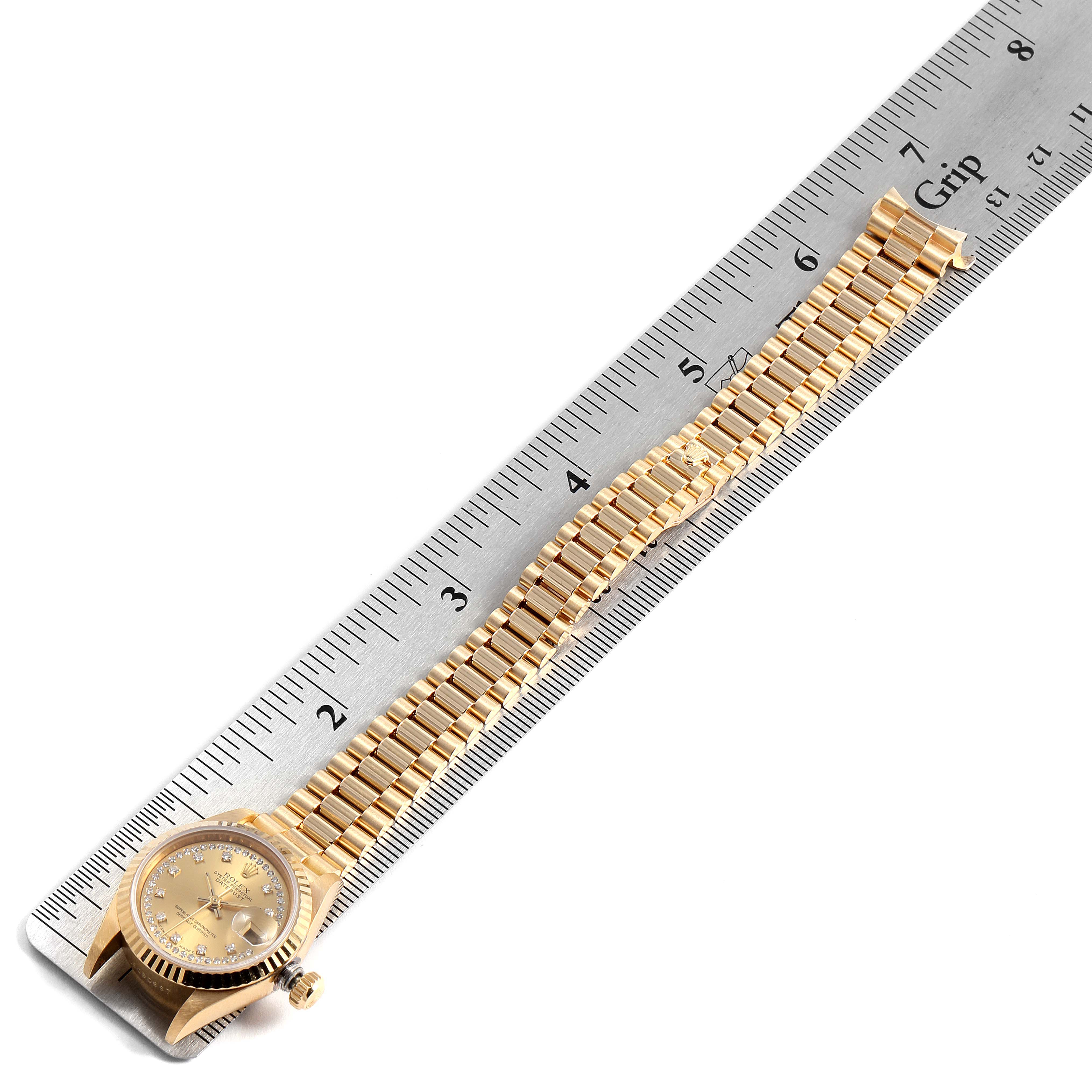 The image shows the Rolex President 69178 Women's Yellow Gold Champagne Dial 69178 Women's Yellow Gold Champagne Dial model watch laying flat with a metal ruler indicating the length of its gold band.