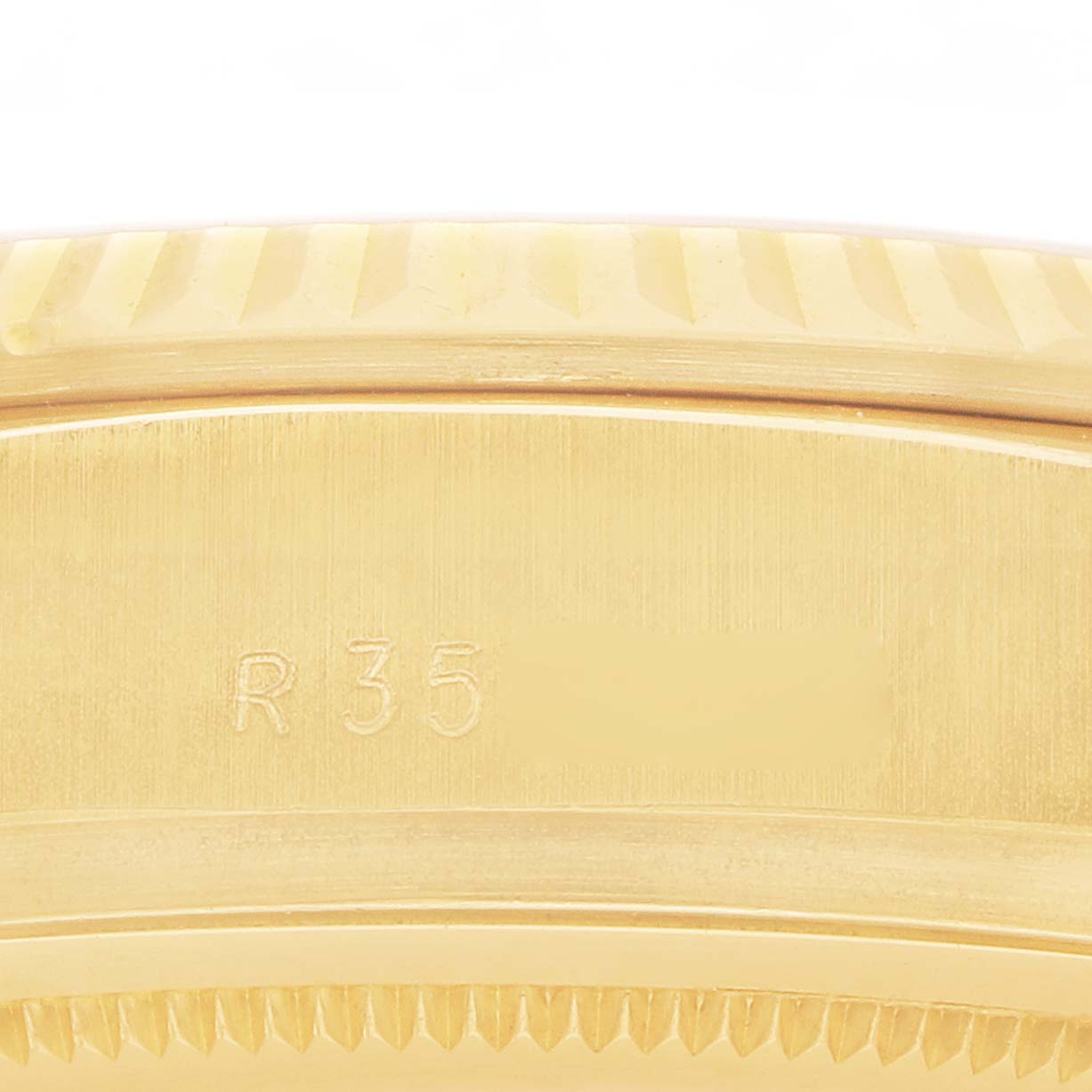 The image shows a close-up of the side view of the bezel and case of a Rolex President 18038 Men
s Yellow Gold Champagne Dial model, focusing on the engraved "R35" and fluted details.