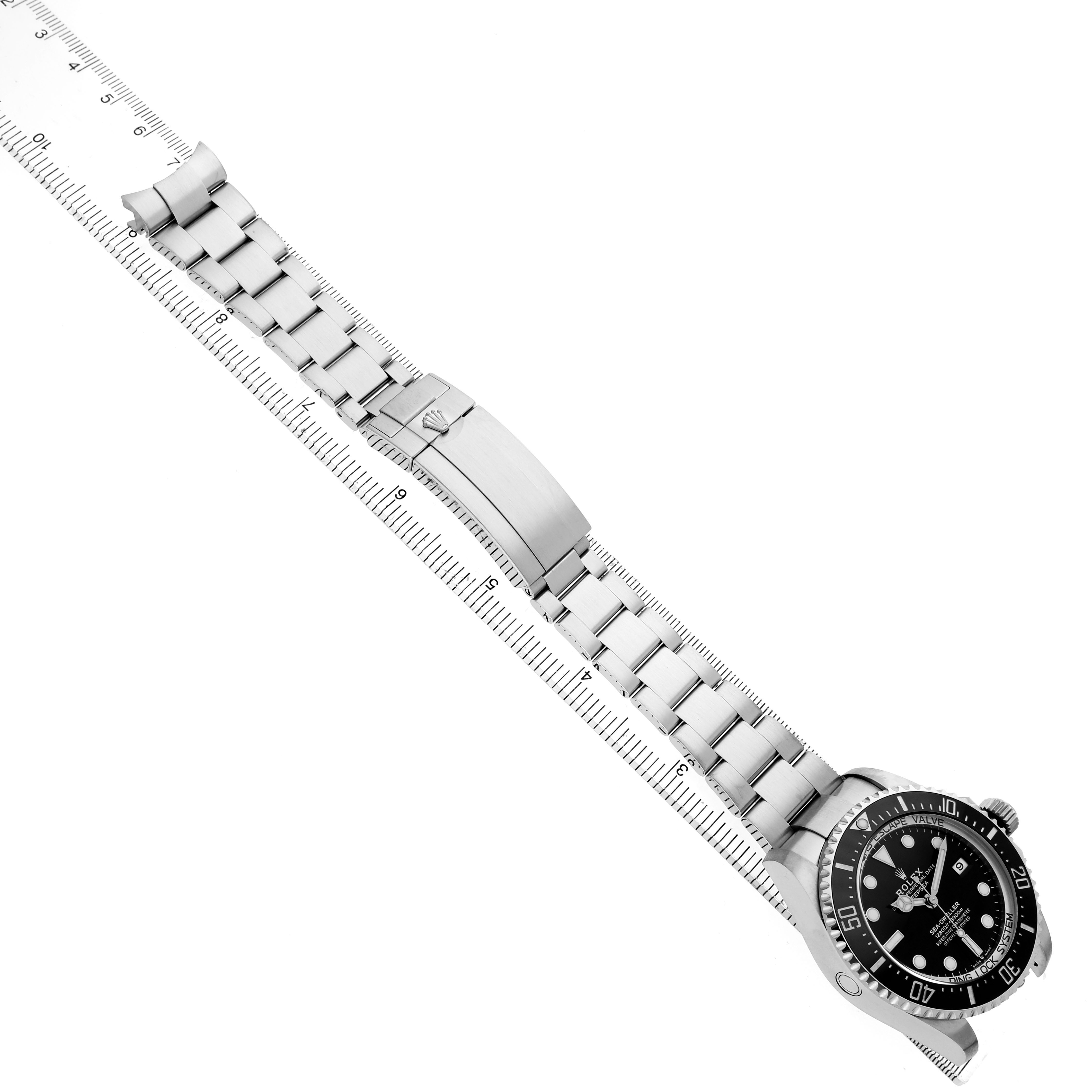 The Rolex Sea-Dweller 136660 Men's Stainless Steel Black Dial watch is shown at an angle, displaying the full bracelet, bezel, and dial alongside a ruler for scale.