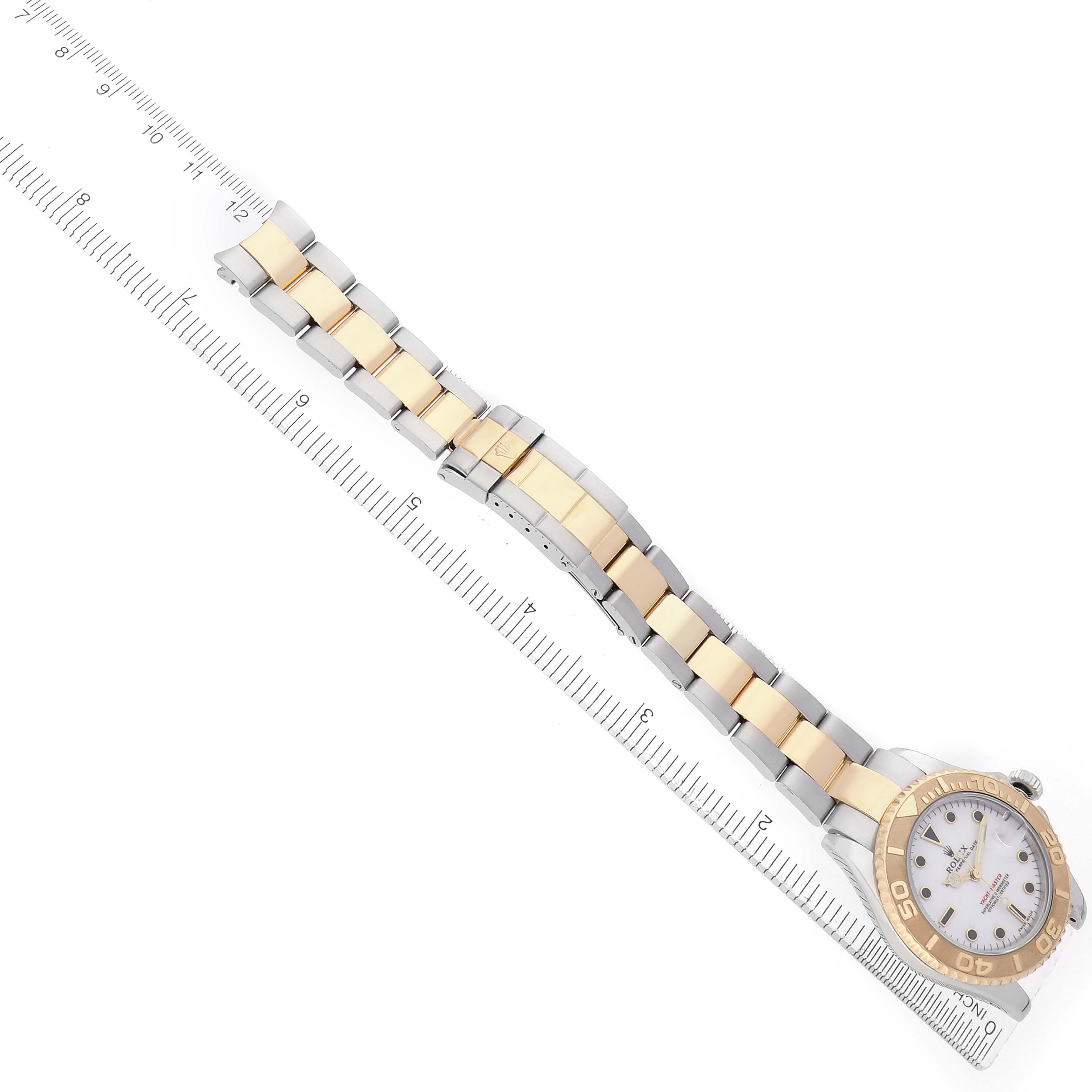 The Rolex Yacht-Master 168623 Men
s Steel and Gold (two tone) White Dial watch is shown from a top-down angle, displaying the face, bezel, and two-tone bracelet alongside a ruler.