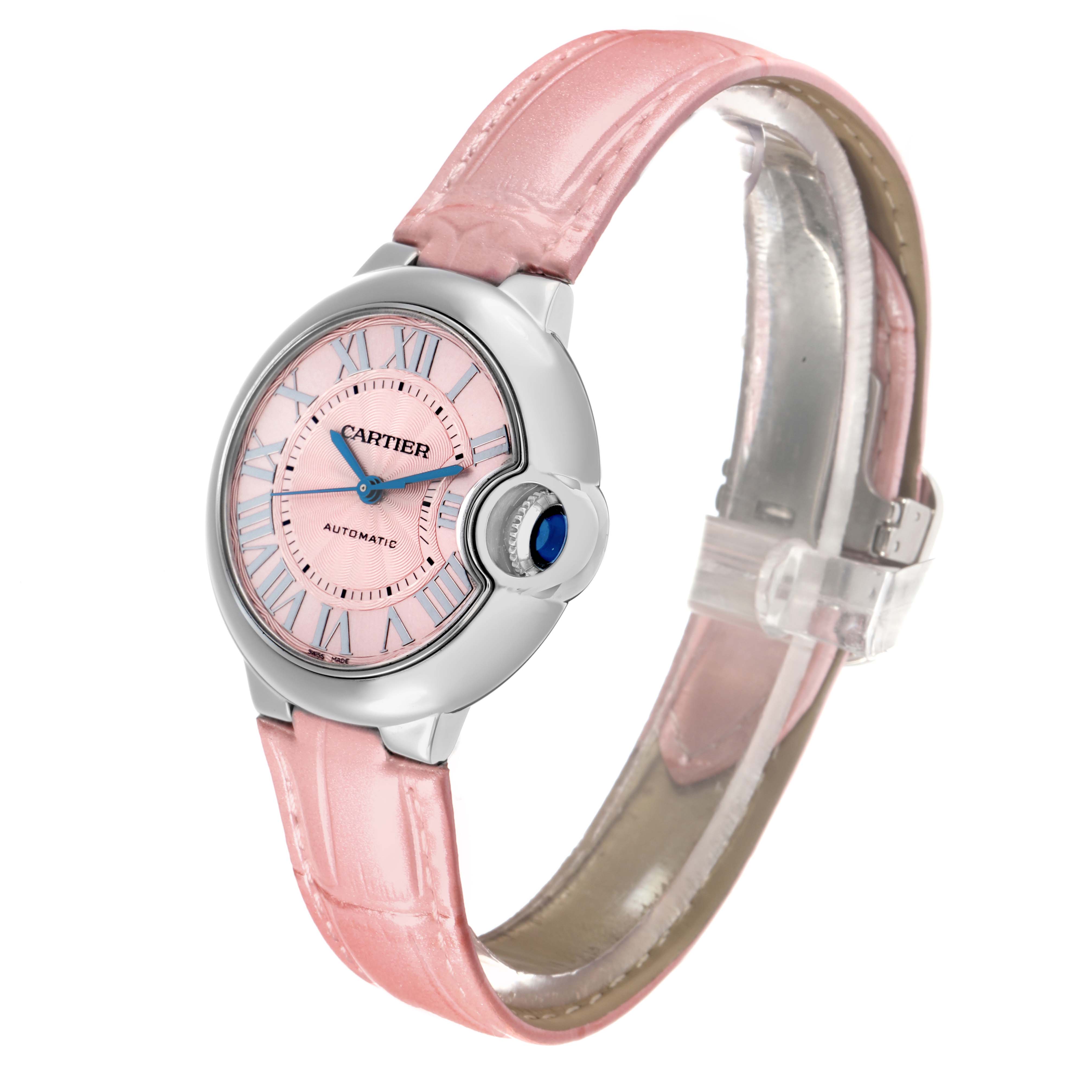 The Ballon Bleu model by Cartier is shown at a slight angle, highlighting its pink dial, blue hands, cabochon crown, and pink strap.
