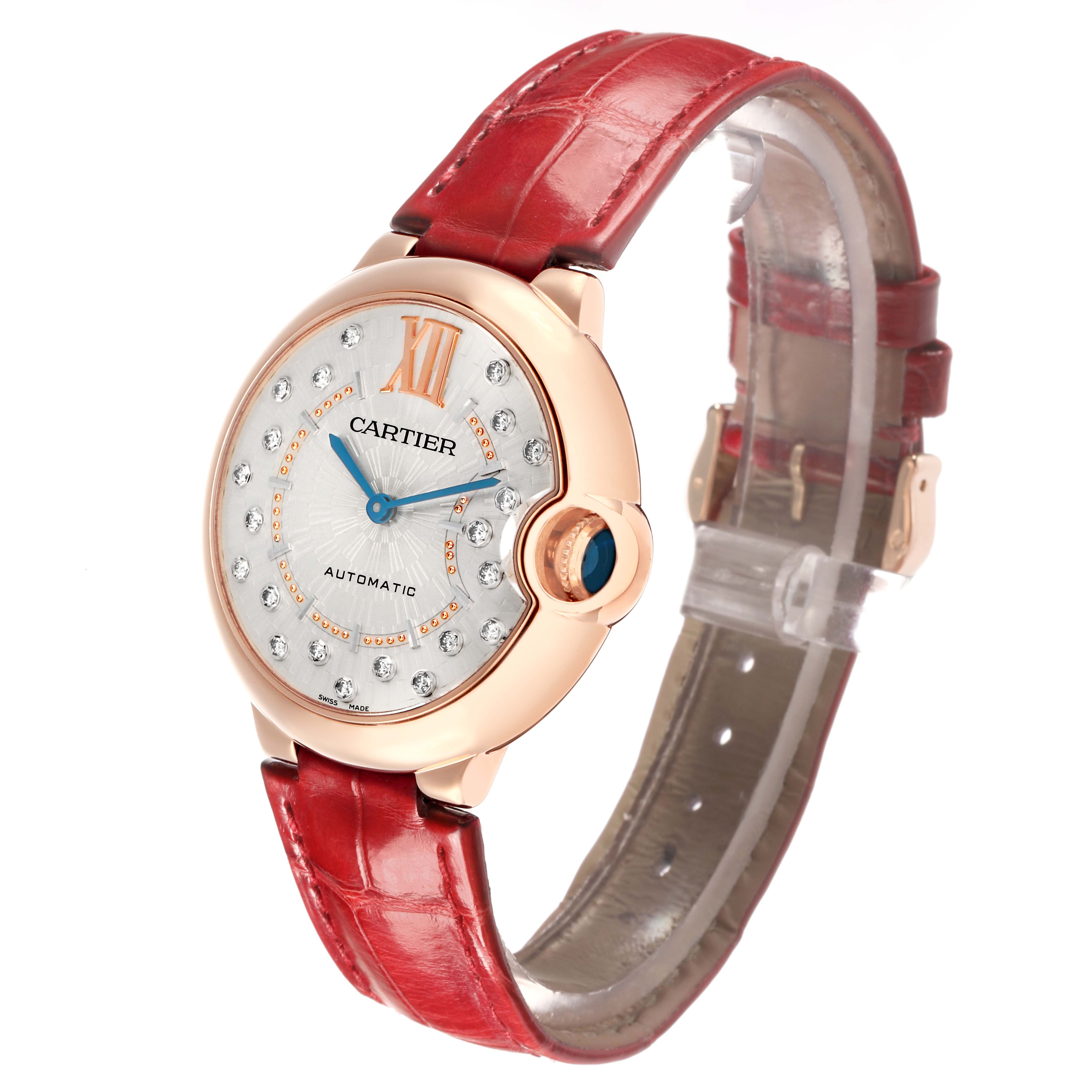 The Ballon Bleu de Cartier watch is shown at a slight angle highlighting the face, bezel, crown, and red strap.