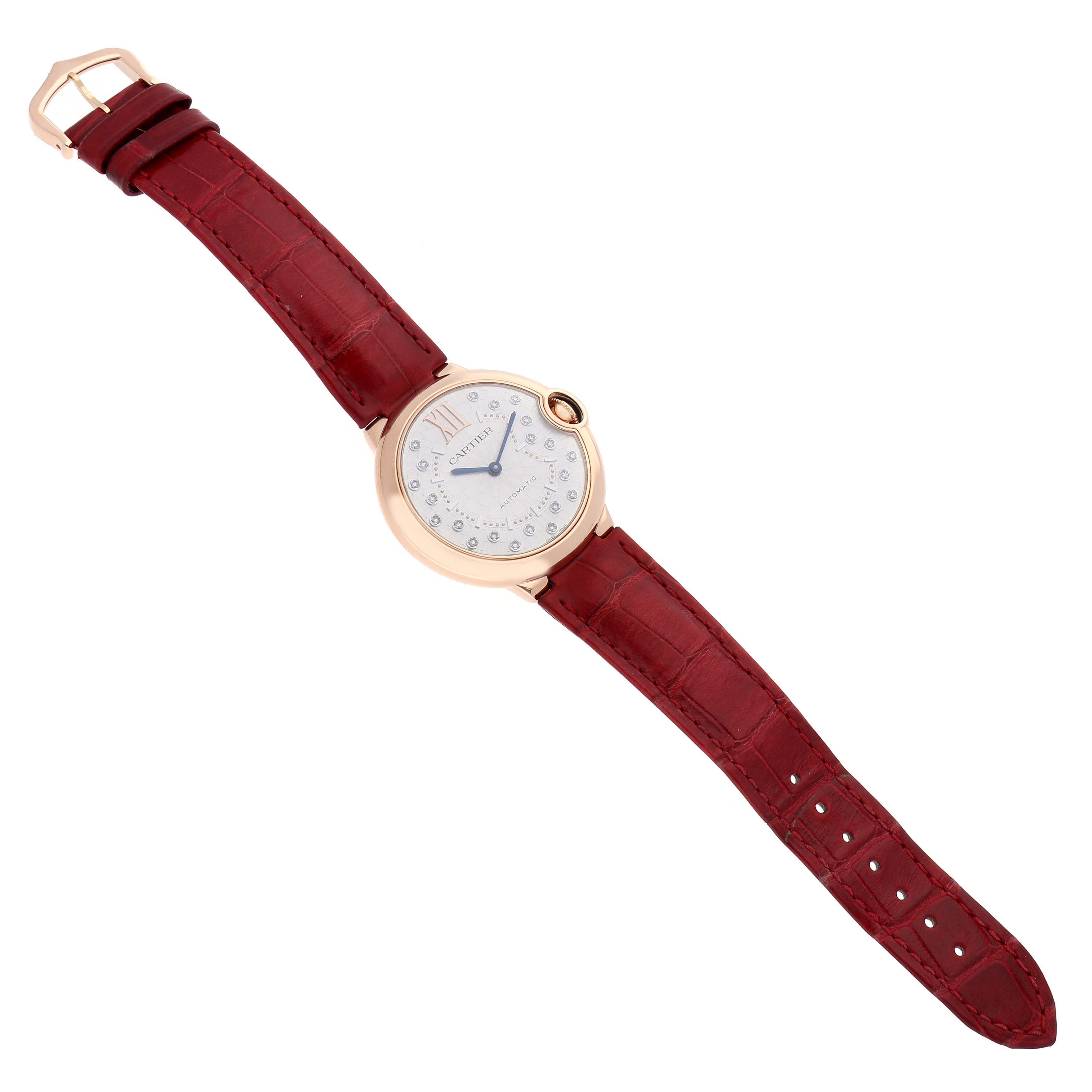 The Cartier Ballon Bleu WGBB0053 Men's Rose Gold Silver Dial watch is shown from a top-down angle, displaying its round case, dial, and red leather strap.