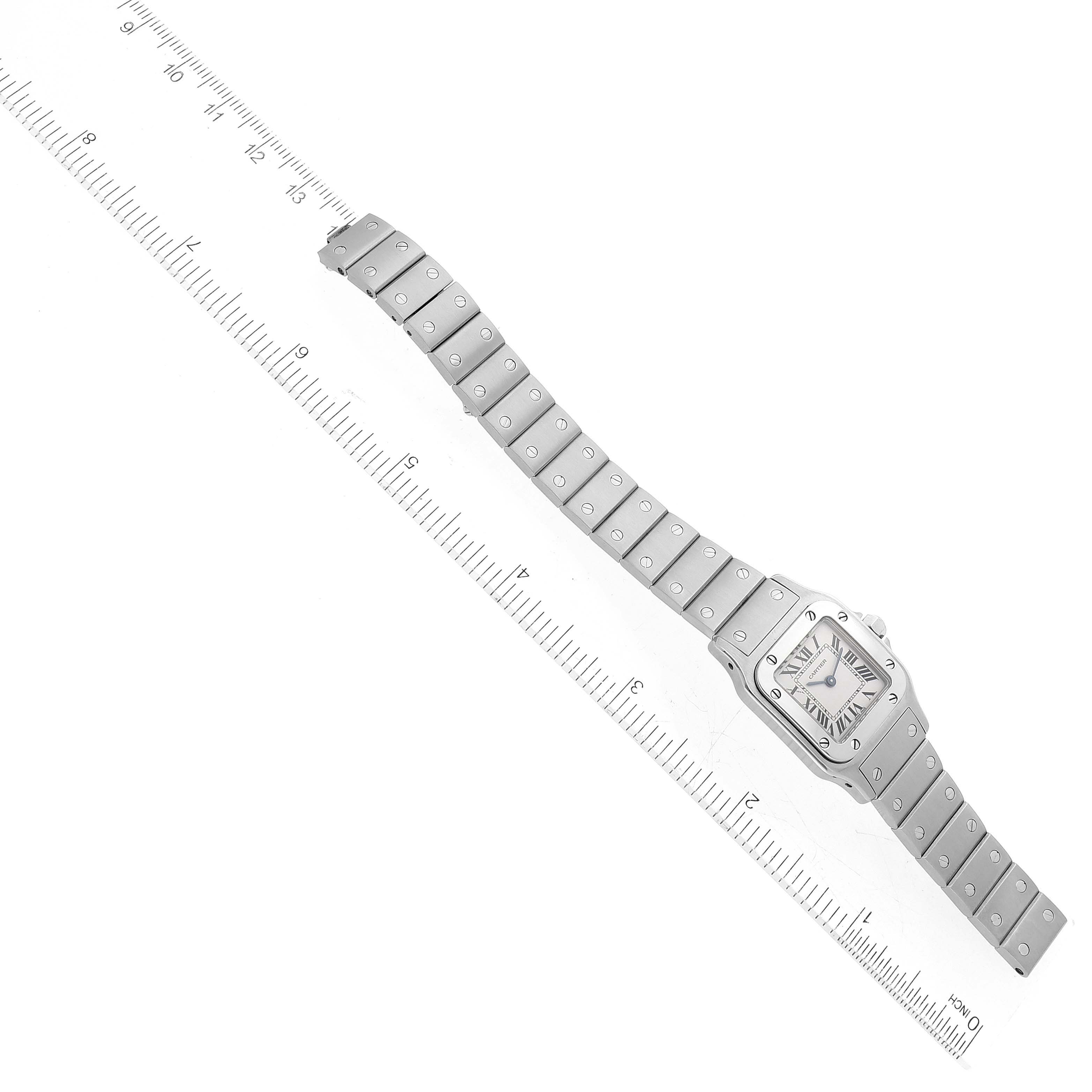 The image shows a top-down view of a Cartier Santos W20056D6 Women's Stainless Steel Silver Dial W20056D6 Women's Stainless Steel Silver Dial watch, including its face and full bracelet on a measuring scale.