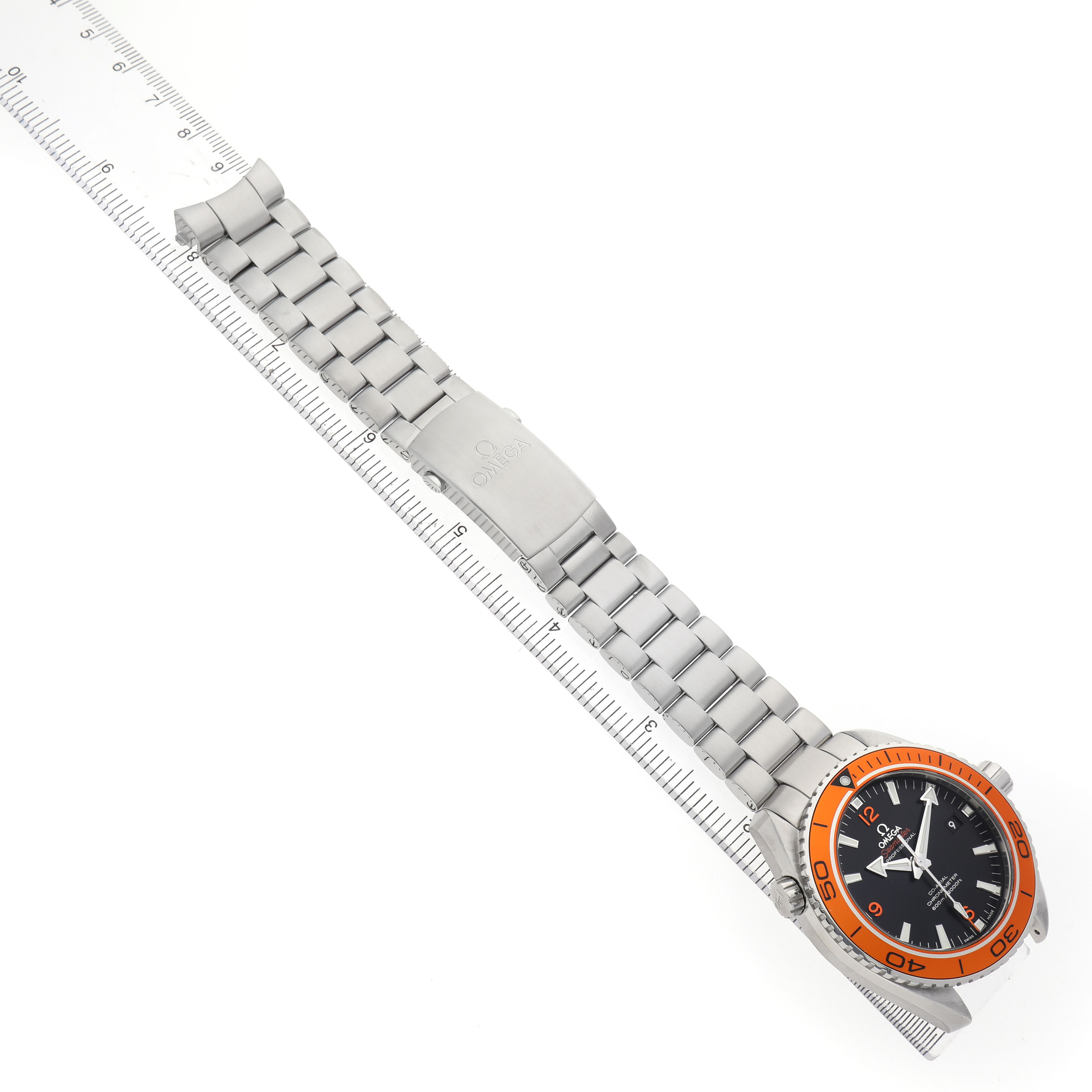 The Omega Seamaster 232.30.46.21.01.002 Men's Stainless Steel Black Dial watch is shown diagonally, displaying the face, bezel, bracelet, and clasp alongside a ruler.