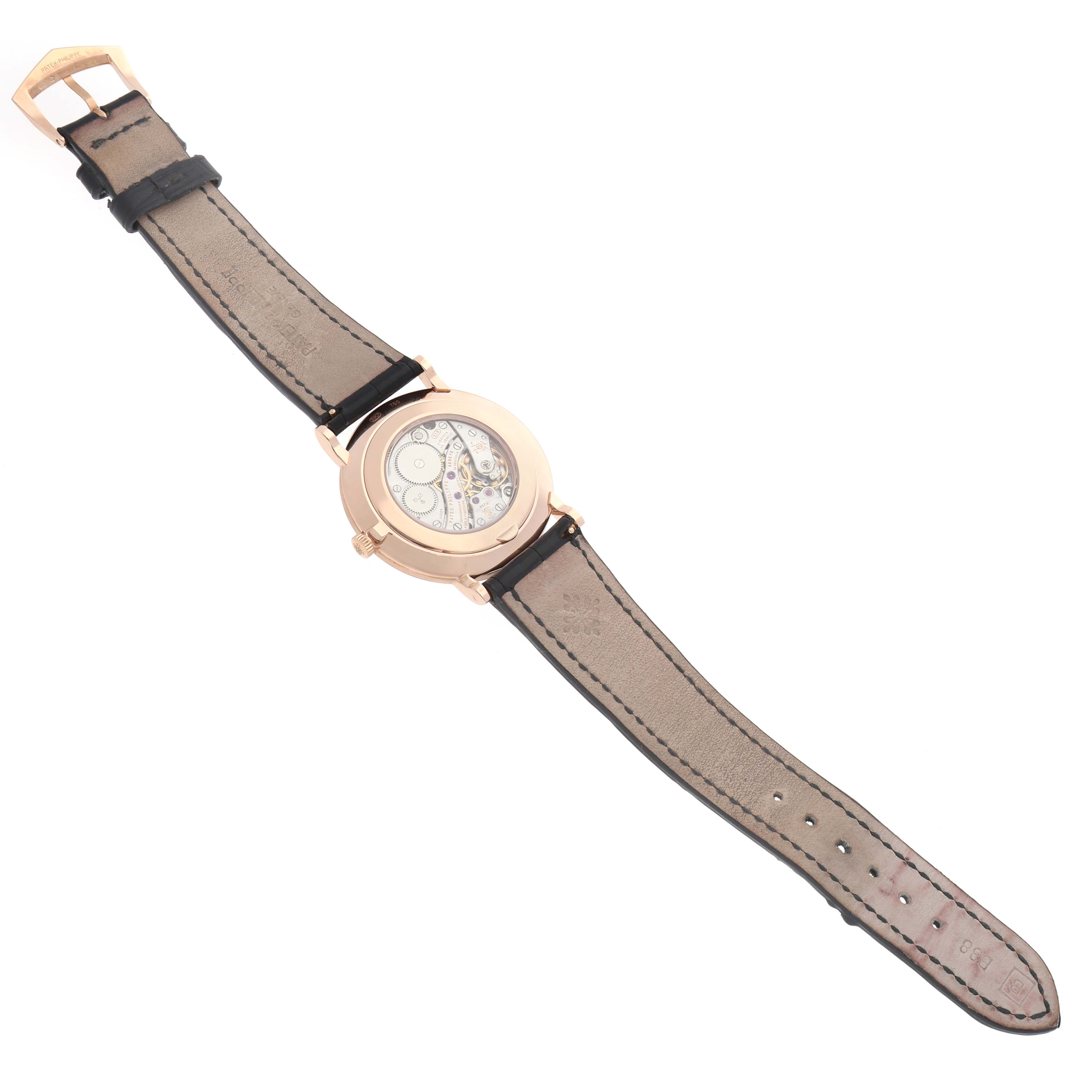 The image shows the back of the Patek Philippe Calatrava 5119 Men
s Rose Gold White Dial watch at an angled view, revealing its internal mechanics and leather strap.