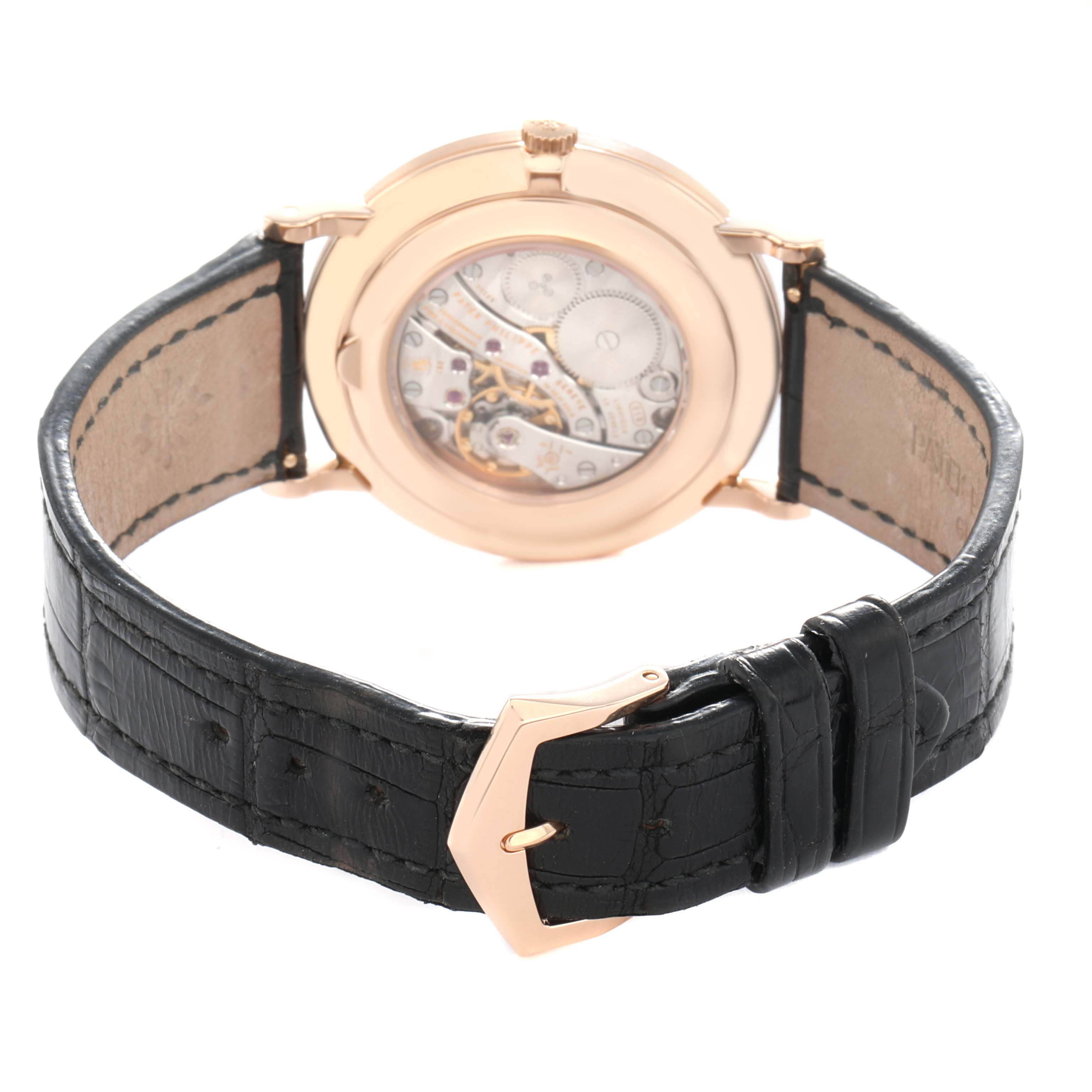 The image shows the back case and exposed movement of a Patek Philippe Calatrava 5119 Men
s Rose Gold White Dial watch, focusing on the leather strap and buckle.