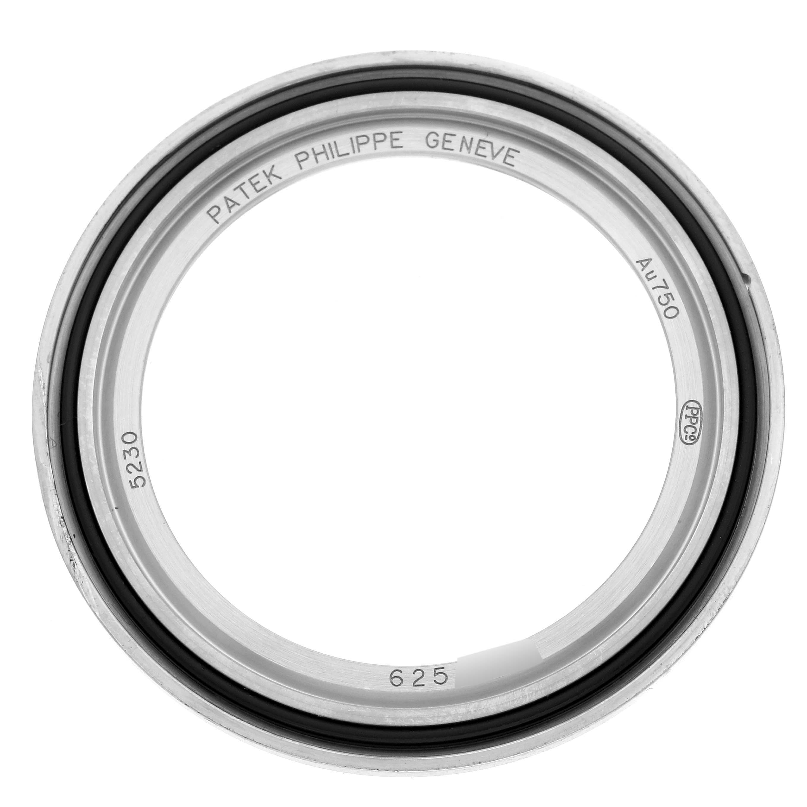 The image shows the bezel of a Patek Philippe Complications 5230G-001 Men's White Gold Grey Dial 5230G-001 Men's White Gold Grey Dial watch, viewed head-on, displaying inscriptions inside.