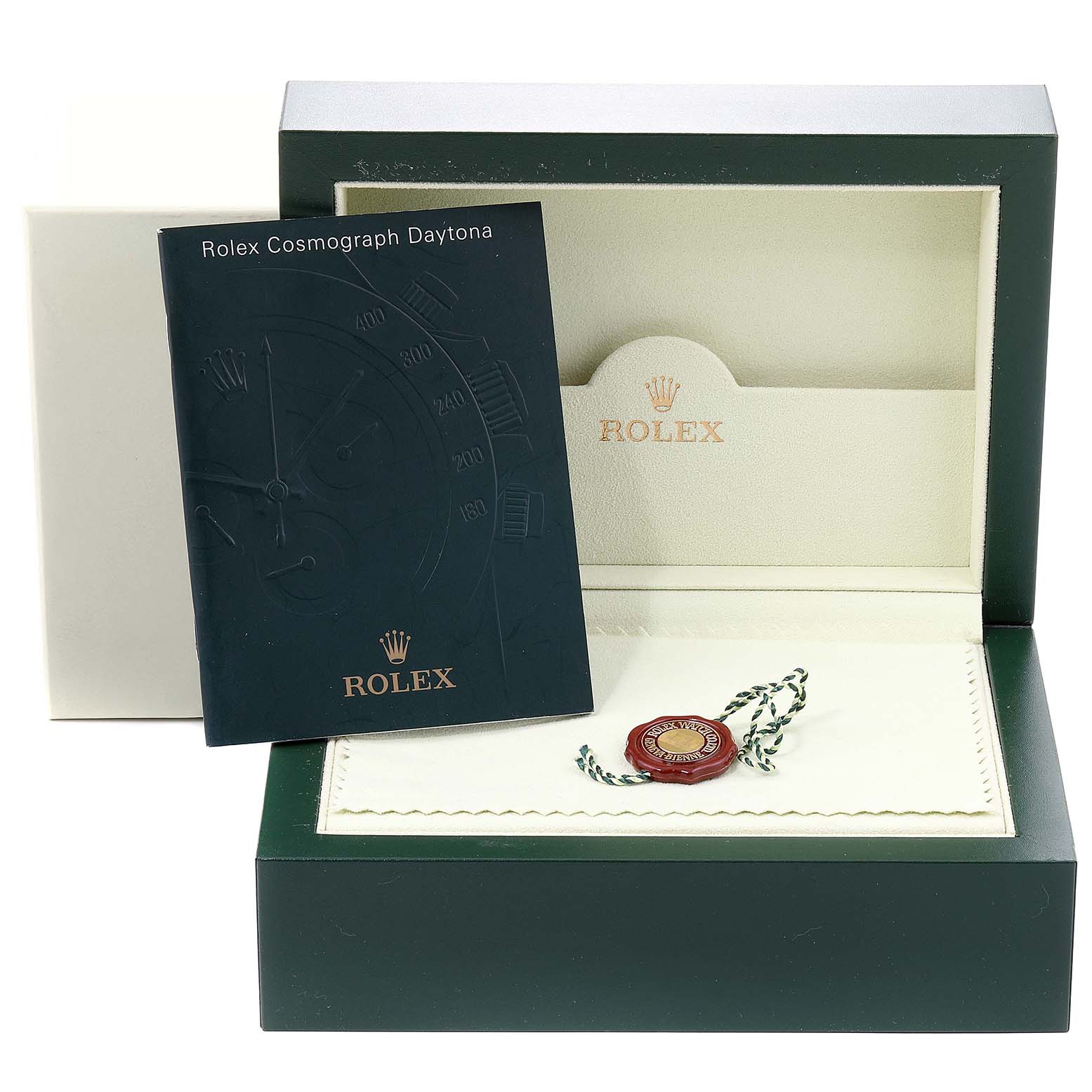The image shows the open packaging for a Rolex Cosmograph Daytona with a booklet and a tag.