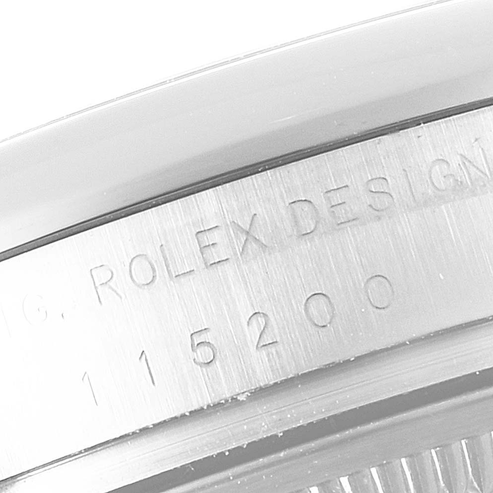 The image shows a close-up of the engraved reference number on the case side of a Rolex Date 115200 Men's Stainless Steel Black Dial 115200 Men's Stainless Steel Black Dial model.