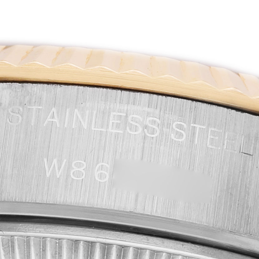The image shows a close-up of the side of a Rolex Datejust 69173 Women's Steel and Gold (two tone) Blue Dial, featuring the fluted bezel and part of the case with engraved text.