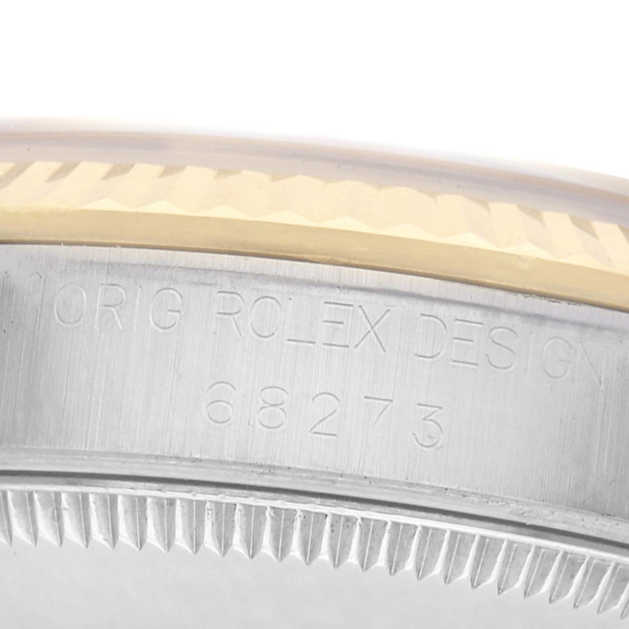 The image shows the side view of a Rolex Mid-Size 68273 Women
s Steel and Gold (two tone) Silver Dial model case, displaying the engraved model number and the edge of the bezel.