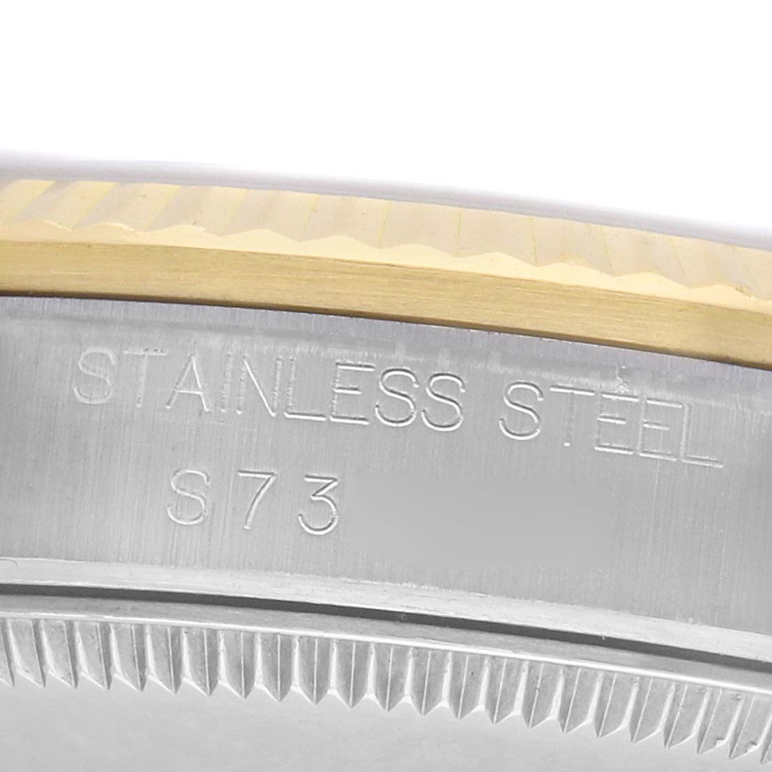 The image shows a close-up side view of the bezel edge of a Mid-Size Rolex watch, highlighting the stainless steel and markings.