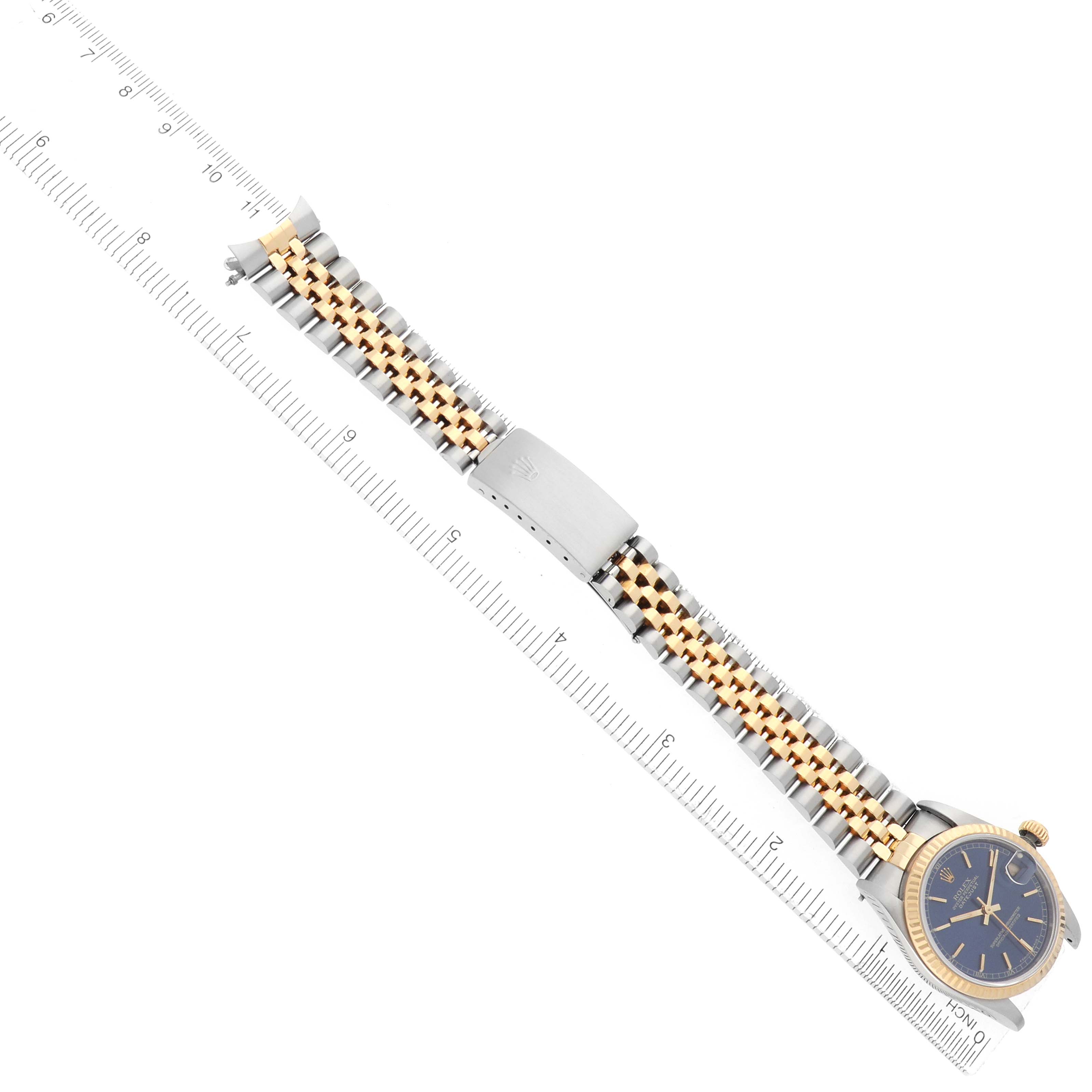 The Rolex Mid-Size 68273 Women
s Steel and Gold (two tone) Blue Dial watch is shown in a top-down angle, highlighting the face, bezel, and two-tone bracelet with a ruler for scale.