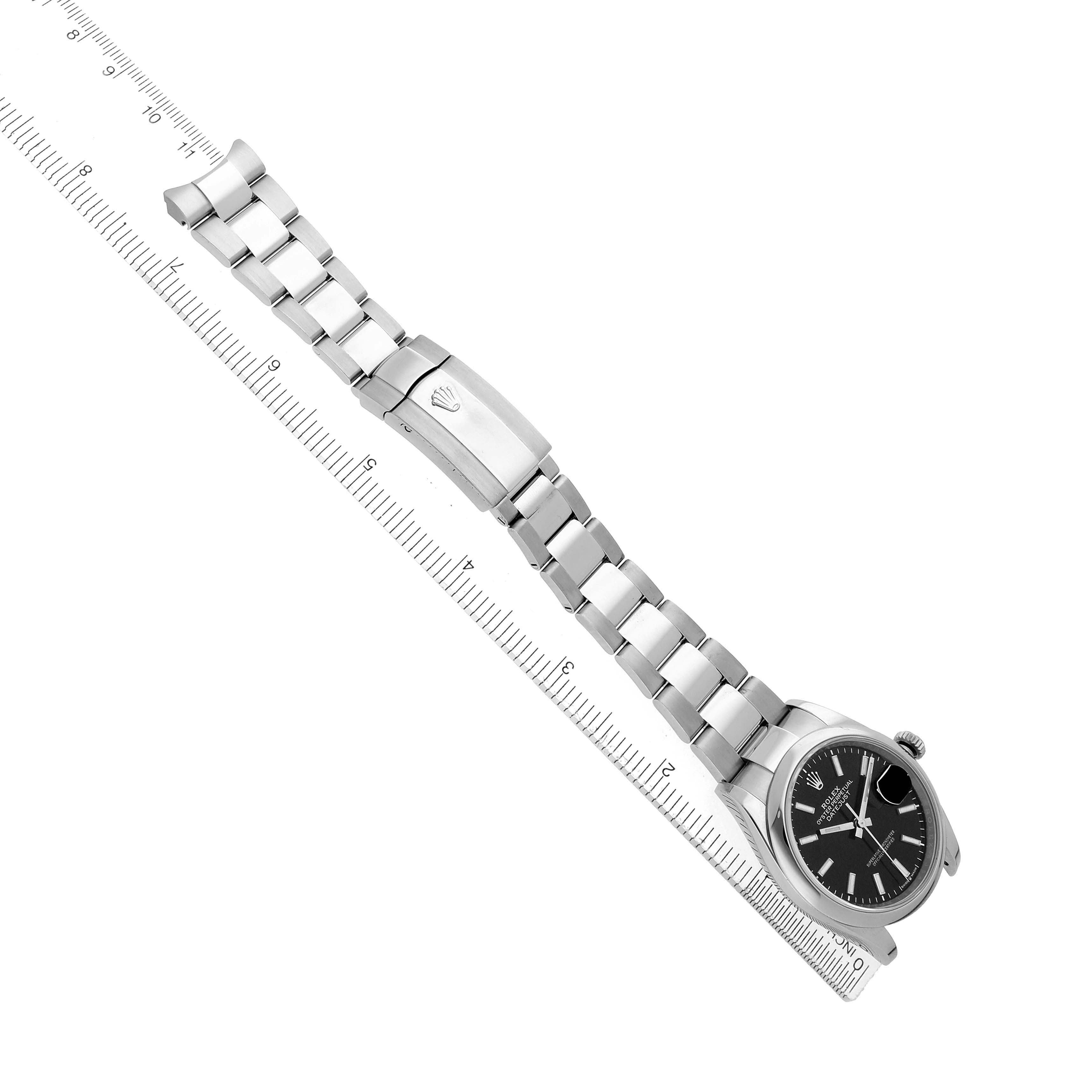 The Rolex Datejust 126200 Men
s Stainless Steel Black Dial watch is shown horizontally, featuring its silver bracelet, clasp, and black dial next to a ruler for scale.