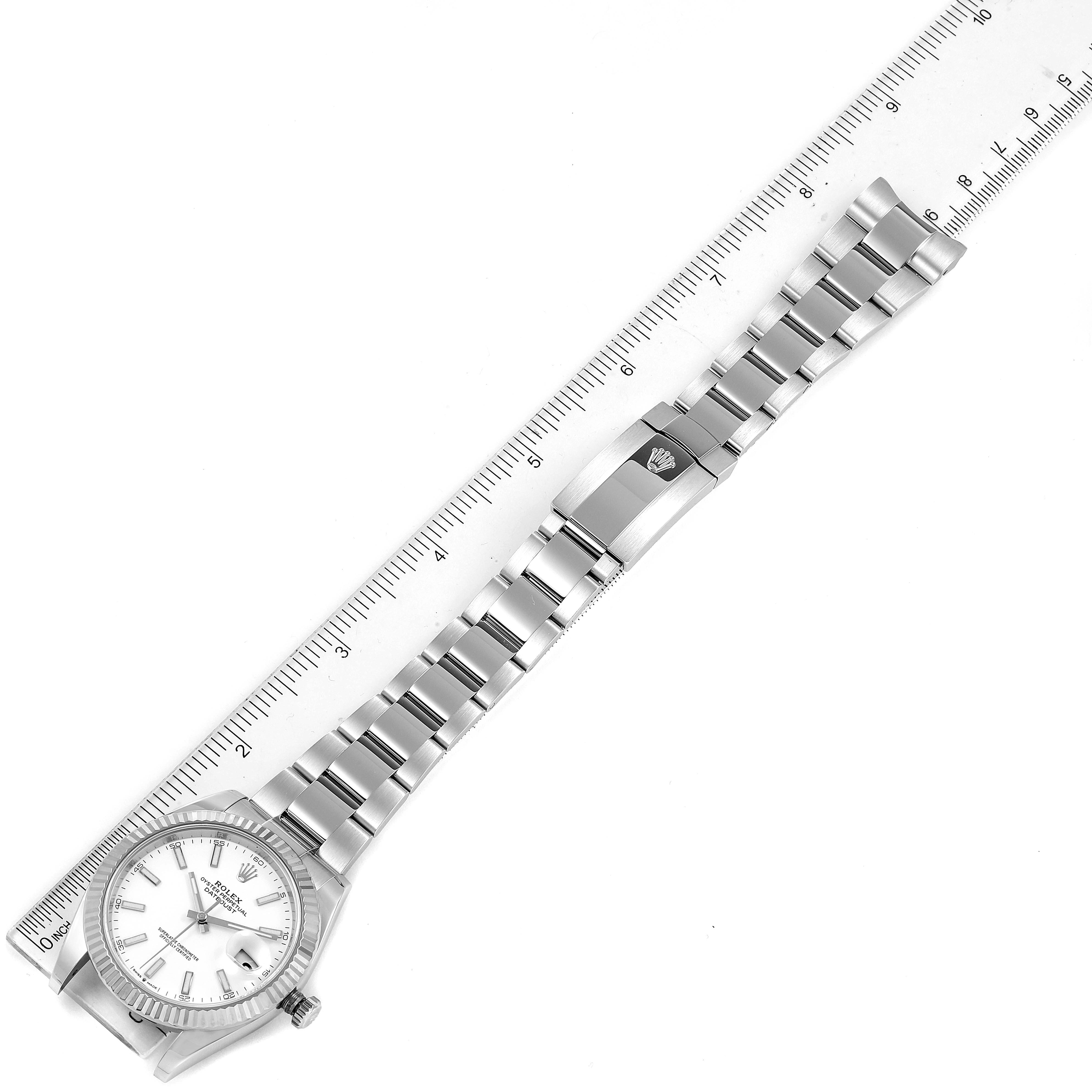 The image shows a top-down view of a Rolex Datejust 41 126334 Men
s Stainless Steel White Dial 126334 Men
s Stainless Steel White Dial watch with a stainless steel bracelet placed alongside a ruler.