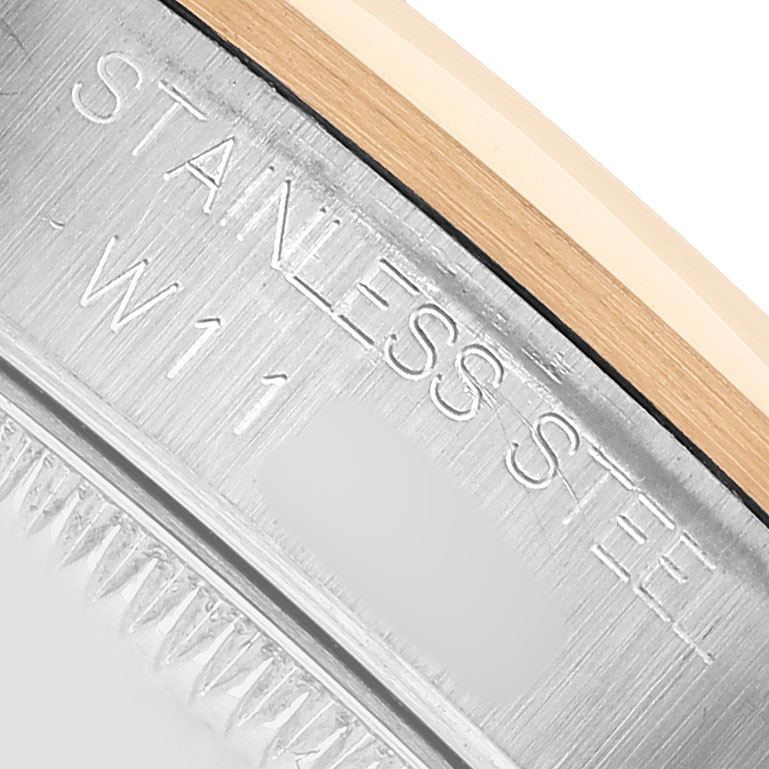 The image shows a close-up of the engraved edge of a Rolex Datejust 68243 Women's Steel and Gold (two tone) Blue Dial model, focusing on the stainless steel and gold parts.