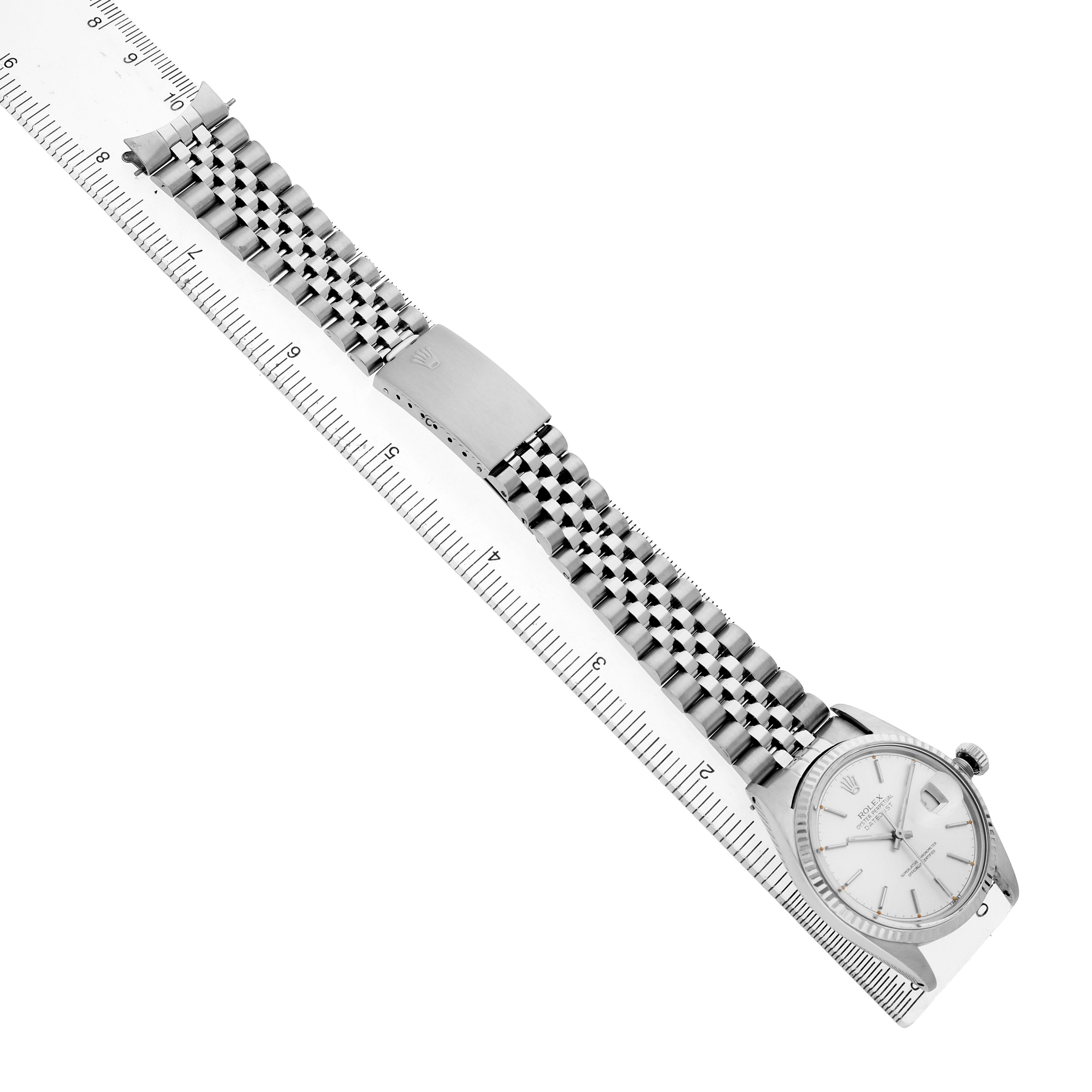 The image shows a Rolex Datejust 16014 Men's Stainless Steel Silver Dial watch from an angled top-down view, highlighting the bracelet, clasp, and face on a ruler.