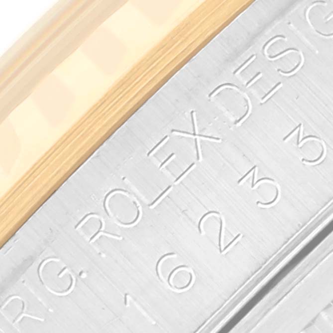 The image shows the side engraving and part of the fluted bezel of a Rolex Datejust 16233 Men's Steel and Gold (two tone) Black Dial 16233 Men's Steel and Gold (two tone) Black Dial watch.