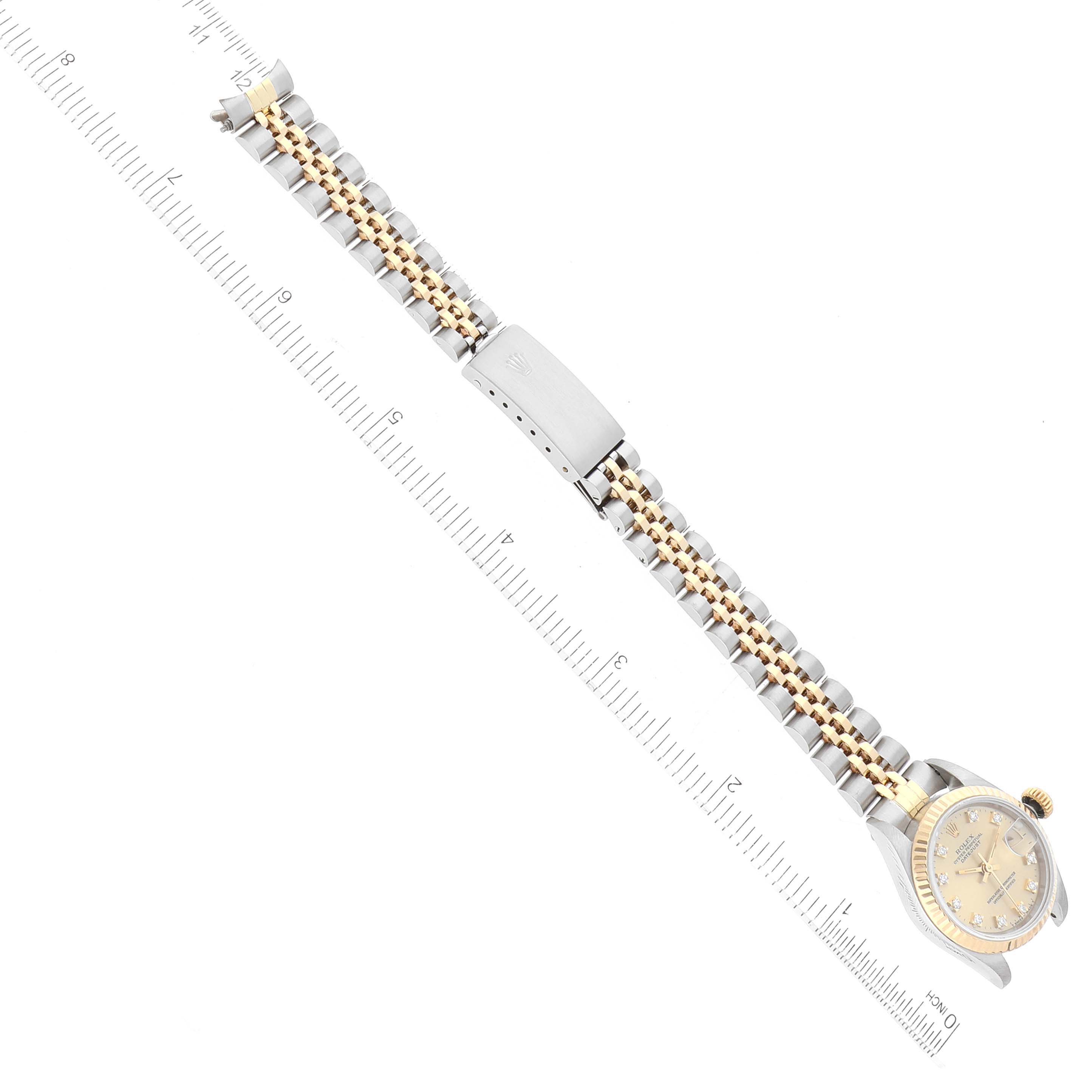 The image shows a Rolex Datejust 69173 Women's Steel and Gold (two tone) Champagne Dial 69173 Women's Steel and Gold (two tone) Champagne Dial watch laying flat with its band fully extended next to a ruler for measurement.