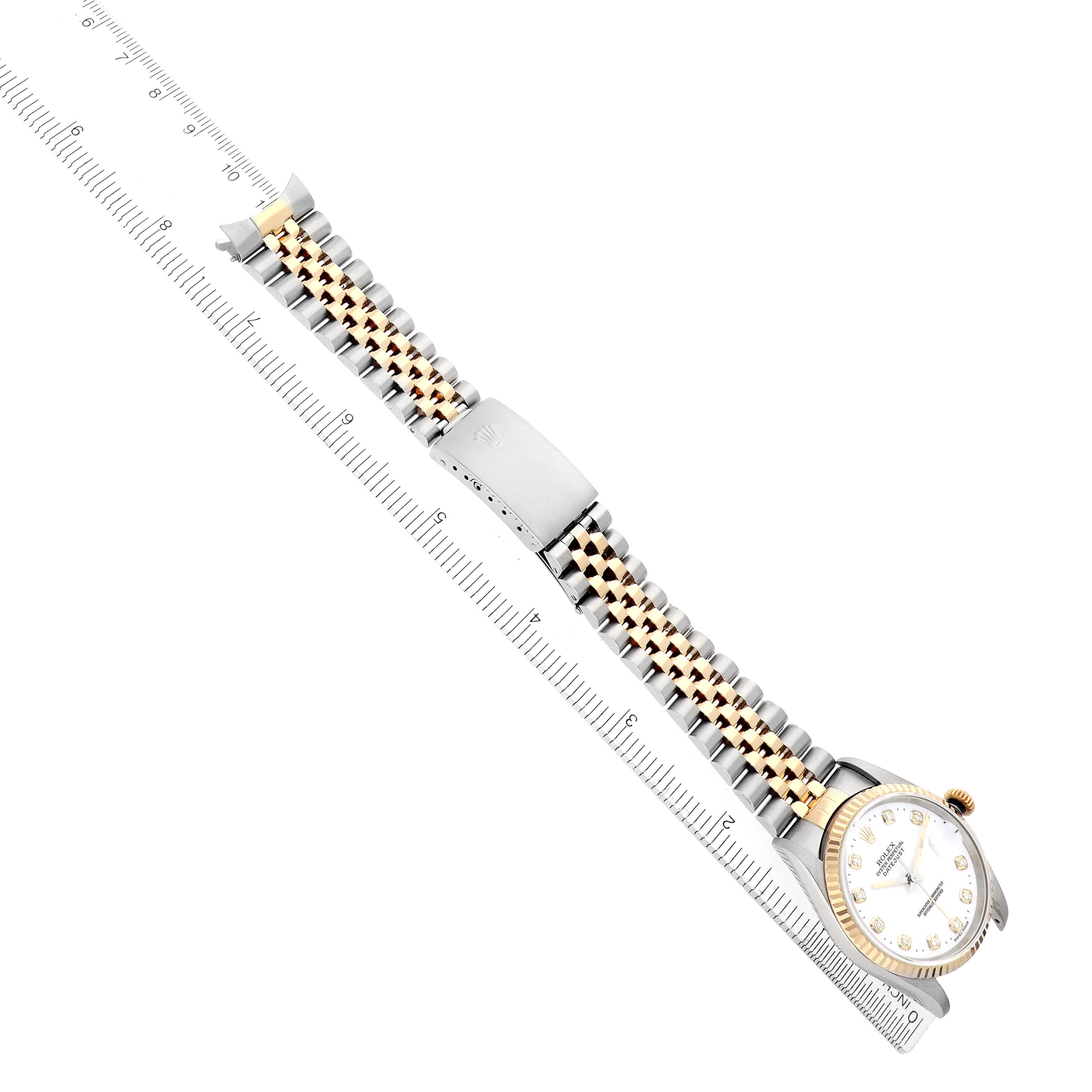 The Rolex Datejust 16233 Men
s Steel and Gold (two tone) White Dial watch is shown from a top angle, displaying the full band, clasp, and watch face, aligned with a ruler.