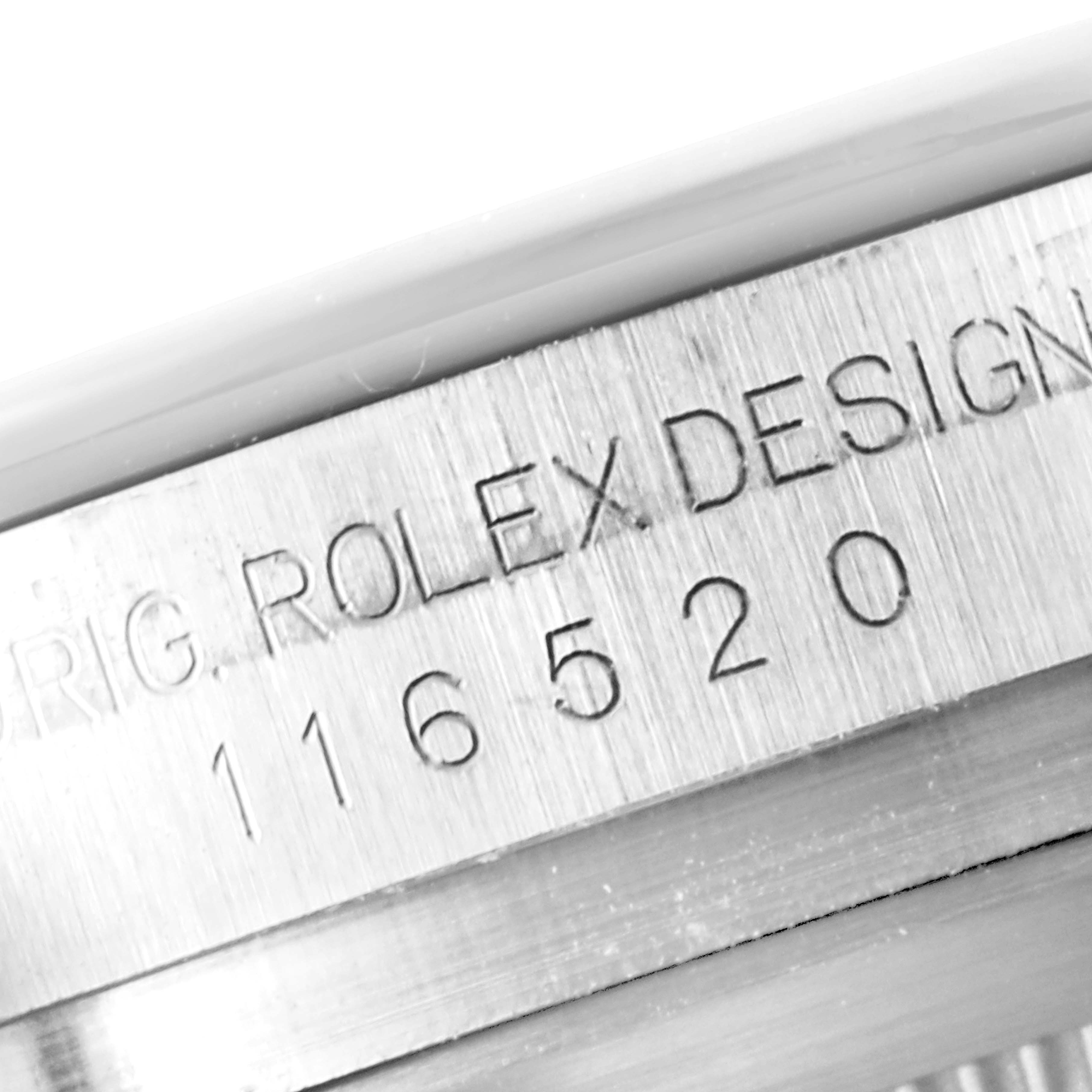 This close-up image shows the engraved serial number and design inscription on the case of the Rolex Daytona 116520 Men's Stainless Steel White Dial 116520 Men's Stainless Steel White Dial watch.