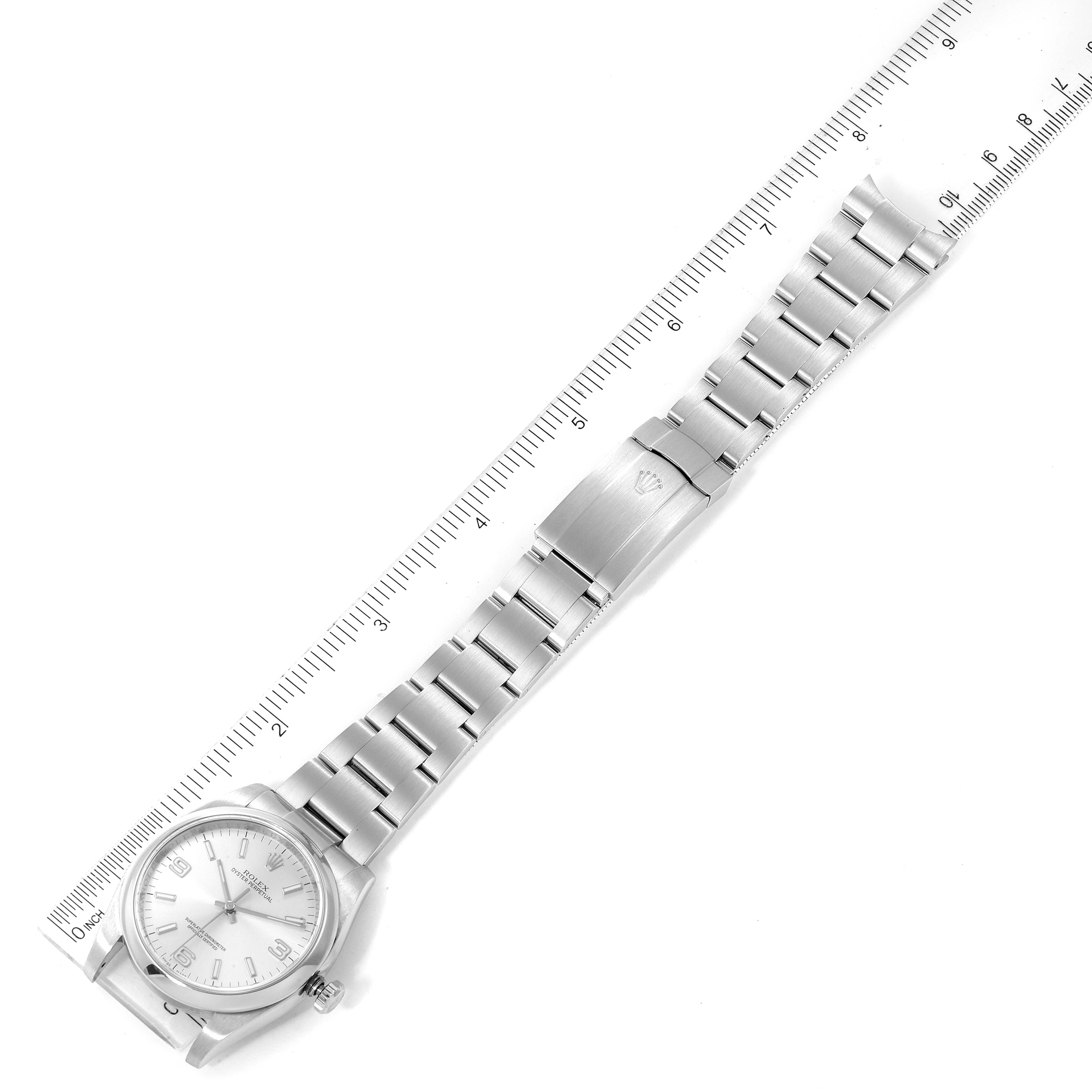 The image shows the entire length of a Rolex Oyster Perpetual 116000 Men's Stainless Steel Silver Dial 116000 Men's Stainless Steel Silver Dial watch laying flat, with its stainless steel bracelet extended and a ruler beside it.