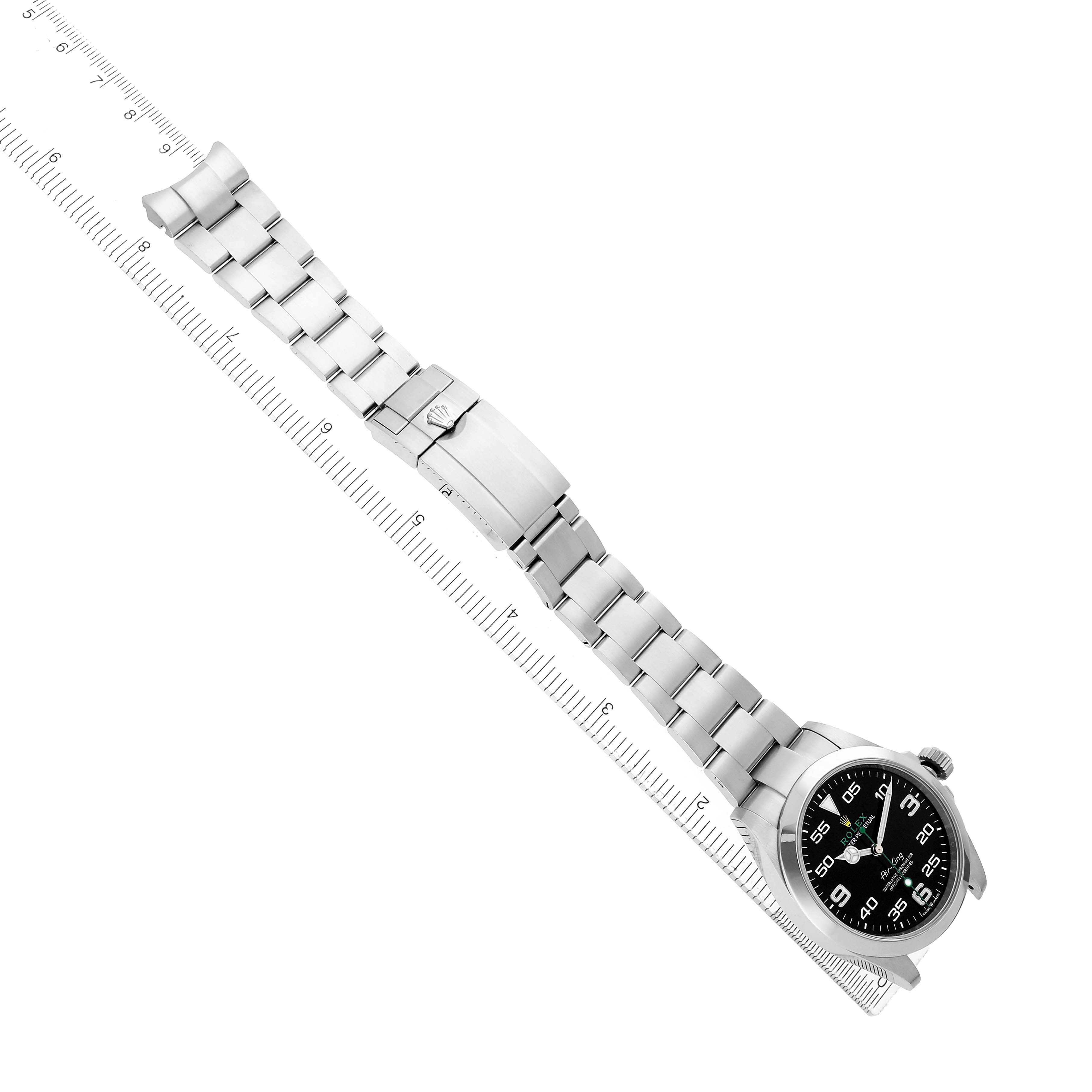 The Rolex Air-King 126900 Men
s Stainless Steel Black Dial watch is shown at an angled top view, displaying the face, bracelet, and clasp on a ruler.