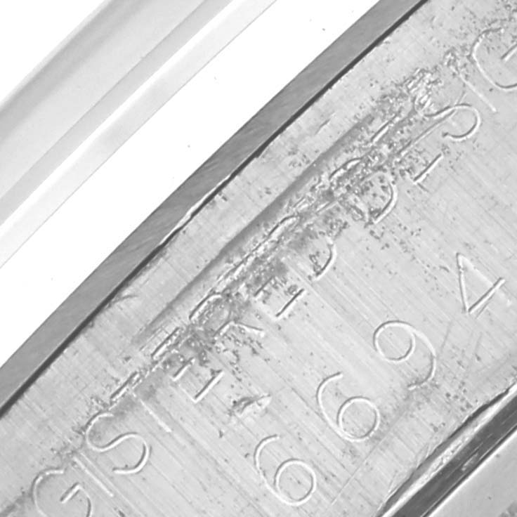 The image shows a close-up of the engraved side of a Rolex Vintage Collection 6694 Men's Stainless Steel Silver Dial 6694 Men's Stainless Steel Silver Dial watch's inner case.