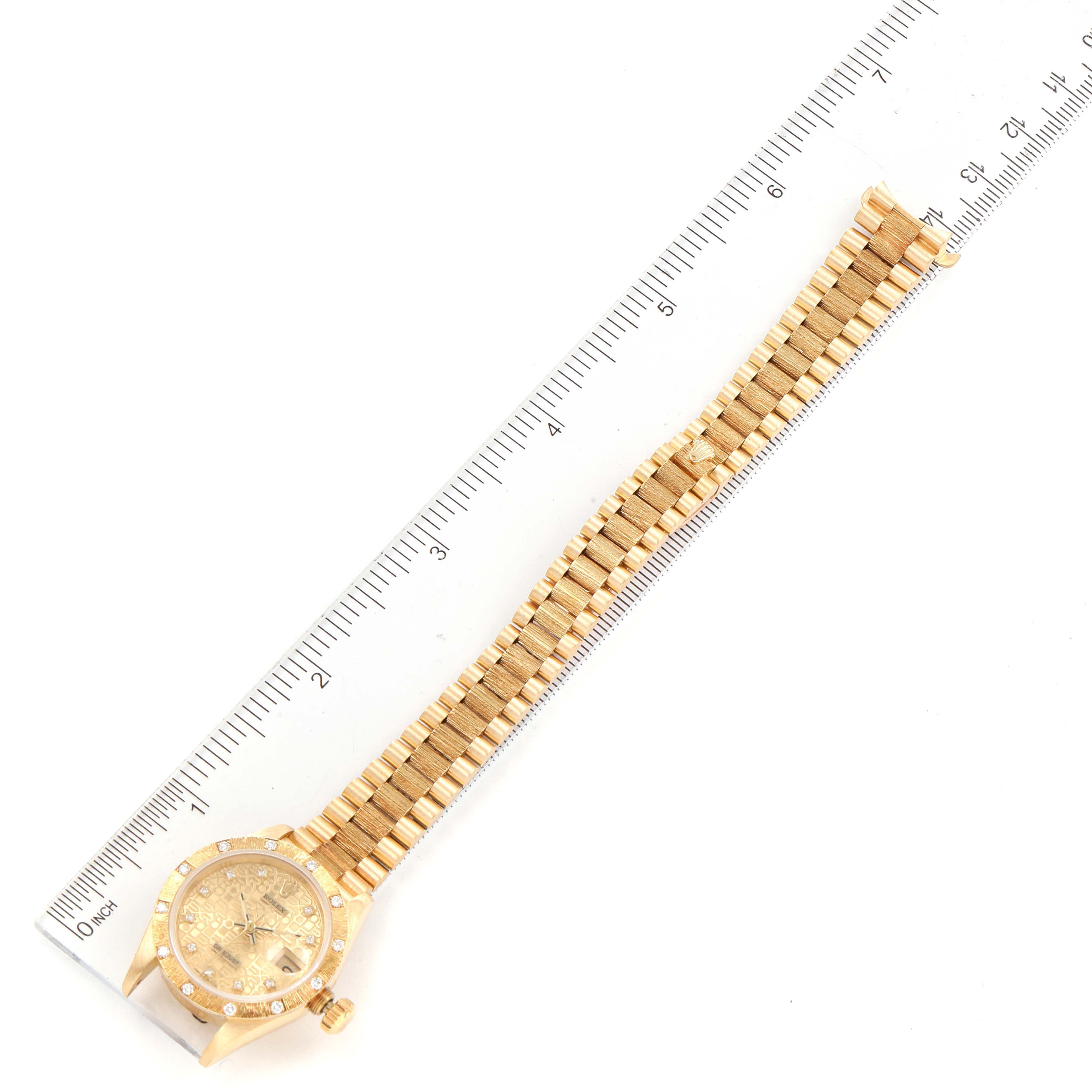 The image shows a top-view angle of the Rolex President 69288 Women
s Yellow Gold Champagne Dial 69288 Women
s Yellow Gold Champagne Dial model watch, focusing on its band and face placed alongside a ruler for scale.