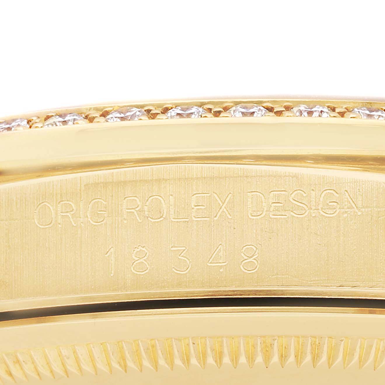 The image shows a close-up of the side of a Rolex President 18348 Men
s Yellow Gold Champagne Dial model, highlighting the engraved "ORIG ROLEX DESIGN" and the bezel with stones.