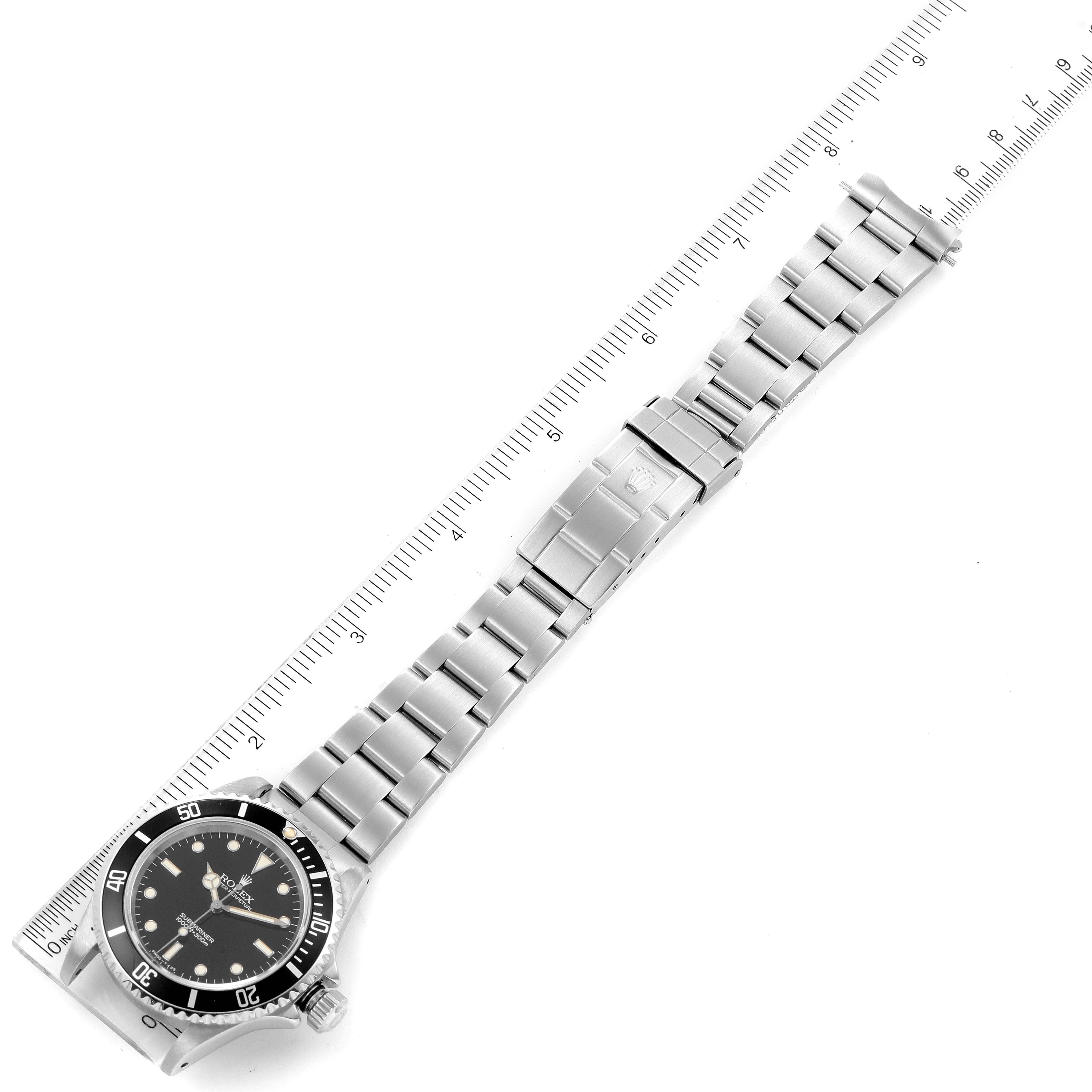 The image shows a top-down view of a Rolex Submariner 14060 Men
s Stainless Steel Black Dial 14060 Men
s Stainless Steel Black Dial watch with its full bracelet and a measuring ruler beside it.