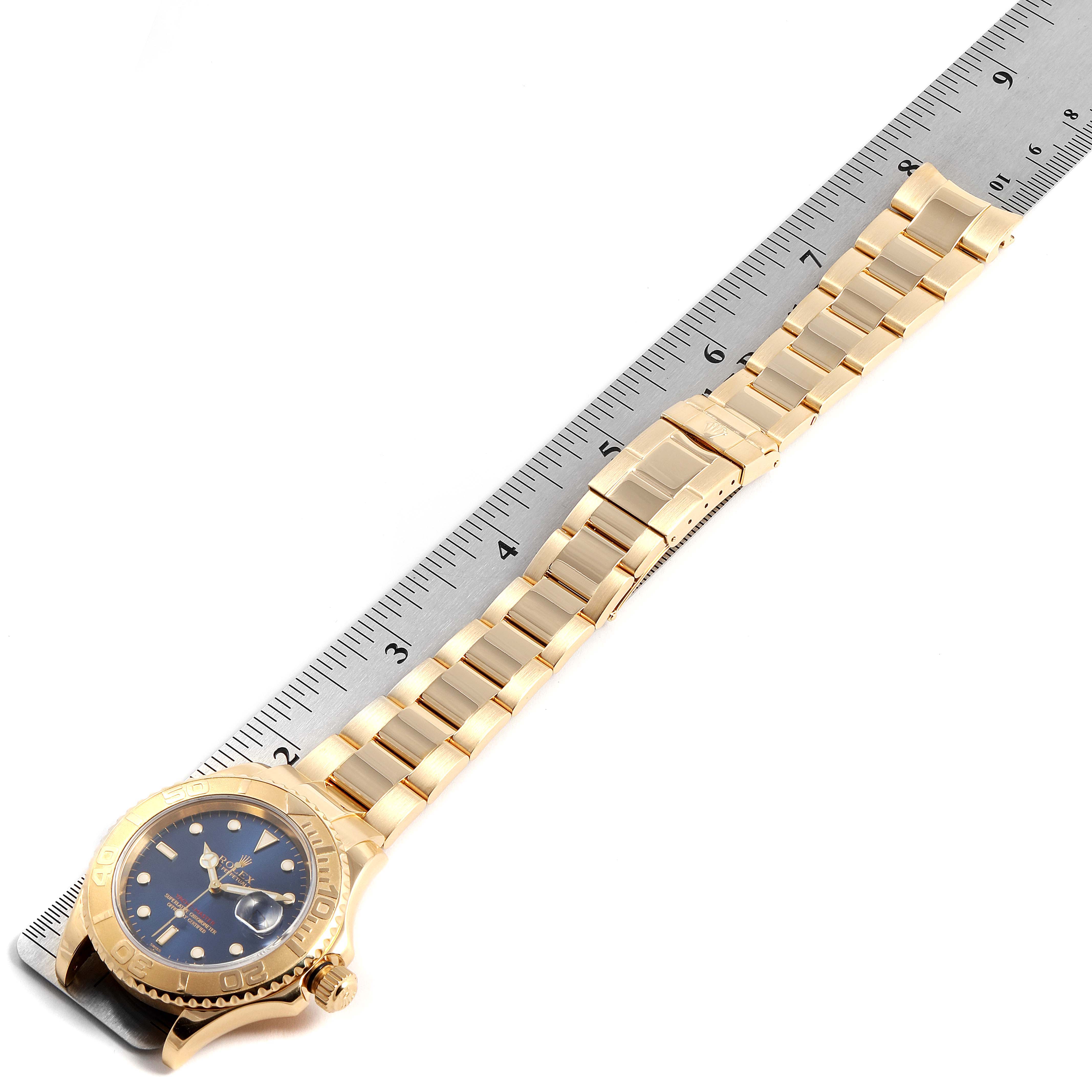 The Rolex Yacht-Master 16628 Men's Yellow Gold Blue Dial 16628 Men's Yellow Gold Blue Dial watch is shown from an angled top-down view, highlighting the bracelet and part of the case, with a ruler for measurement.