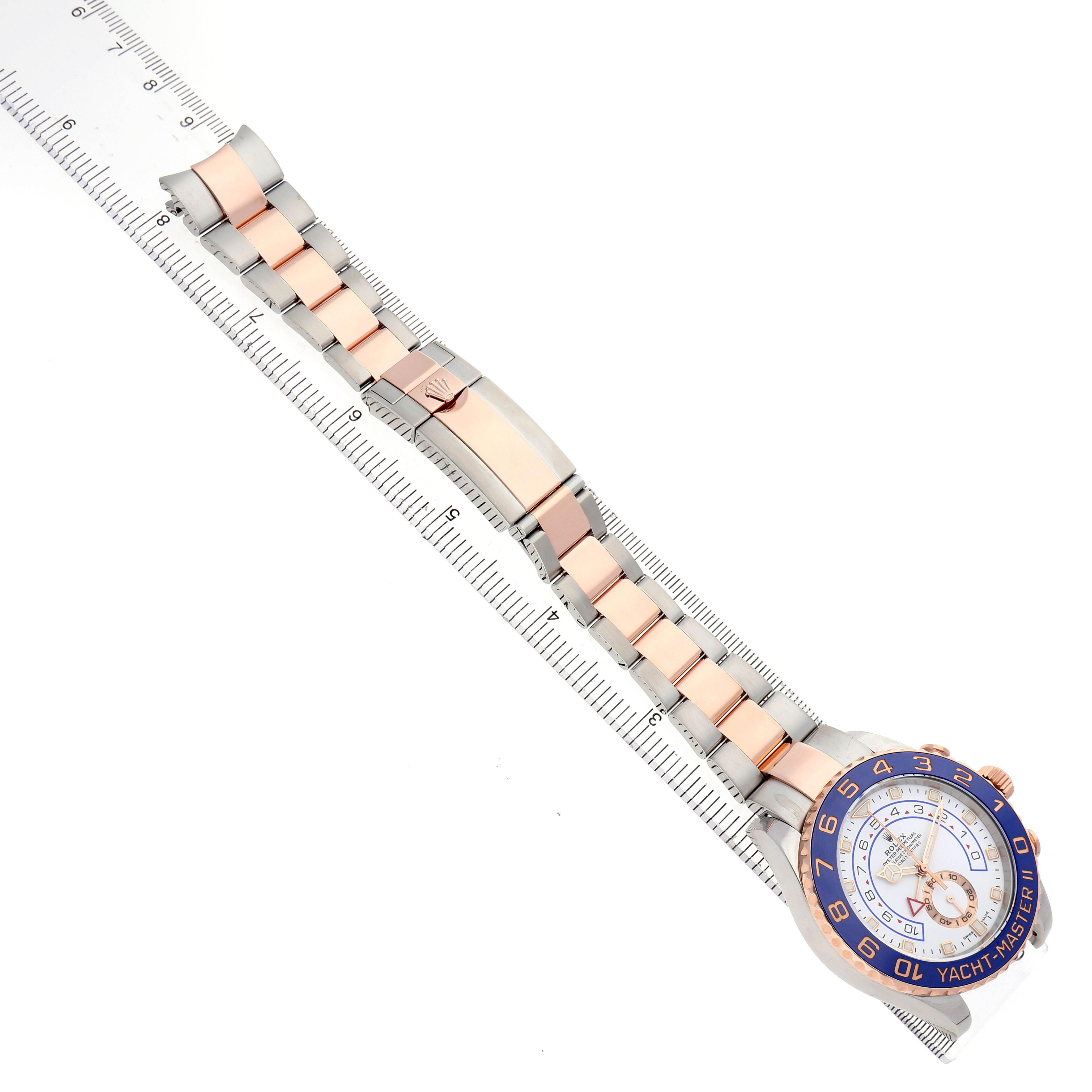 The Rolex Yacht-Master 116681 Men's Steel and Gold (two tone) White Dial watch is shown at an angled side view, displaying the bracelet and face alongside a ruler for scale.