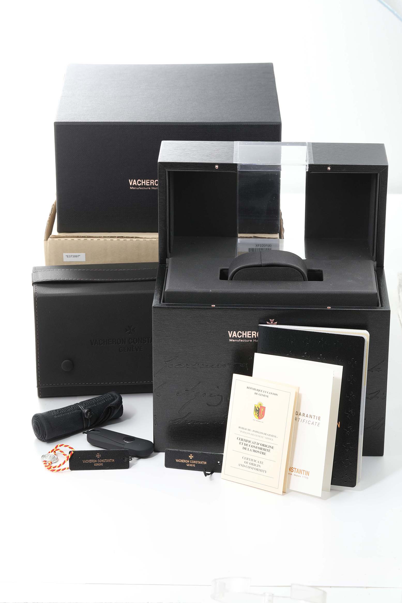 The image shows Vacheron Constantin Patrimony 85180/000R-9166 Men's Rose Gold Grey Dial 85180/000R-9166 Men's Rose Gold Grey Dial watch accessories, including boxes, manuals, a hangtag, and a case, viewed from the front.