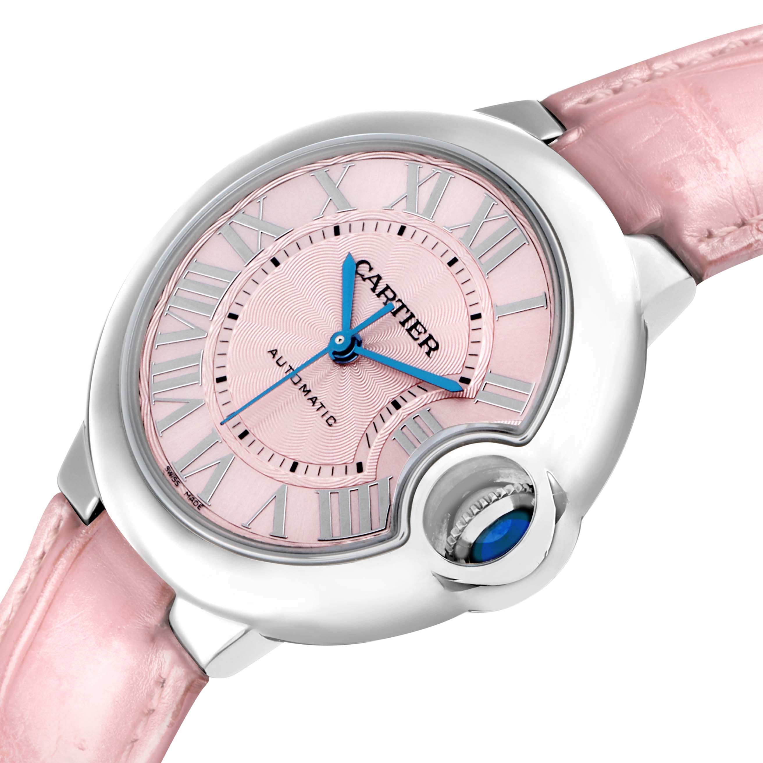 The Cartier Ballon Bleu WSBB0002 Women
s Stainless Steel Pink Dial watch is shown at an angled close-up, highlighting the pink dial, Roman numerals, and crown with a blue cabochon.