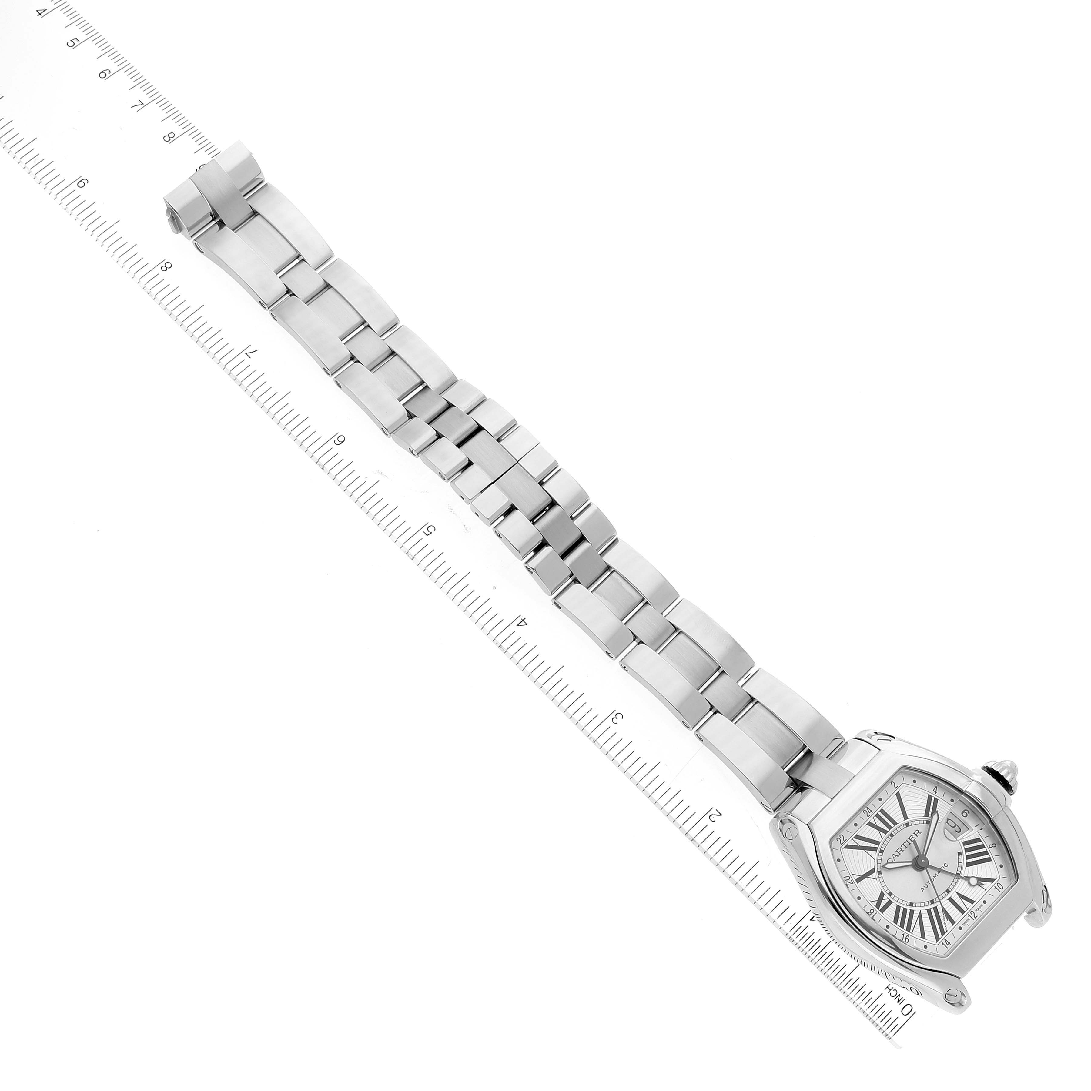 The image shows a Cartier Roadster W62032X6 Men's Stainless Steel Silver Dial W62032X6 Men's Stainless Steel Silver Dial watch lying flat with its face, bracelet, and clasp fully visible alongside a measurement ruler.