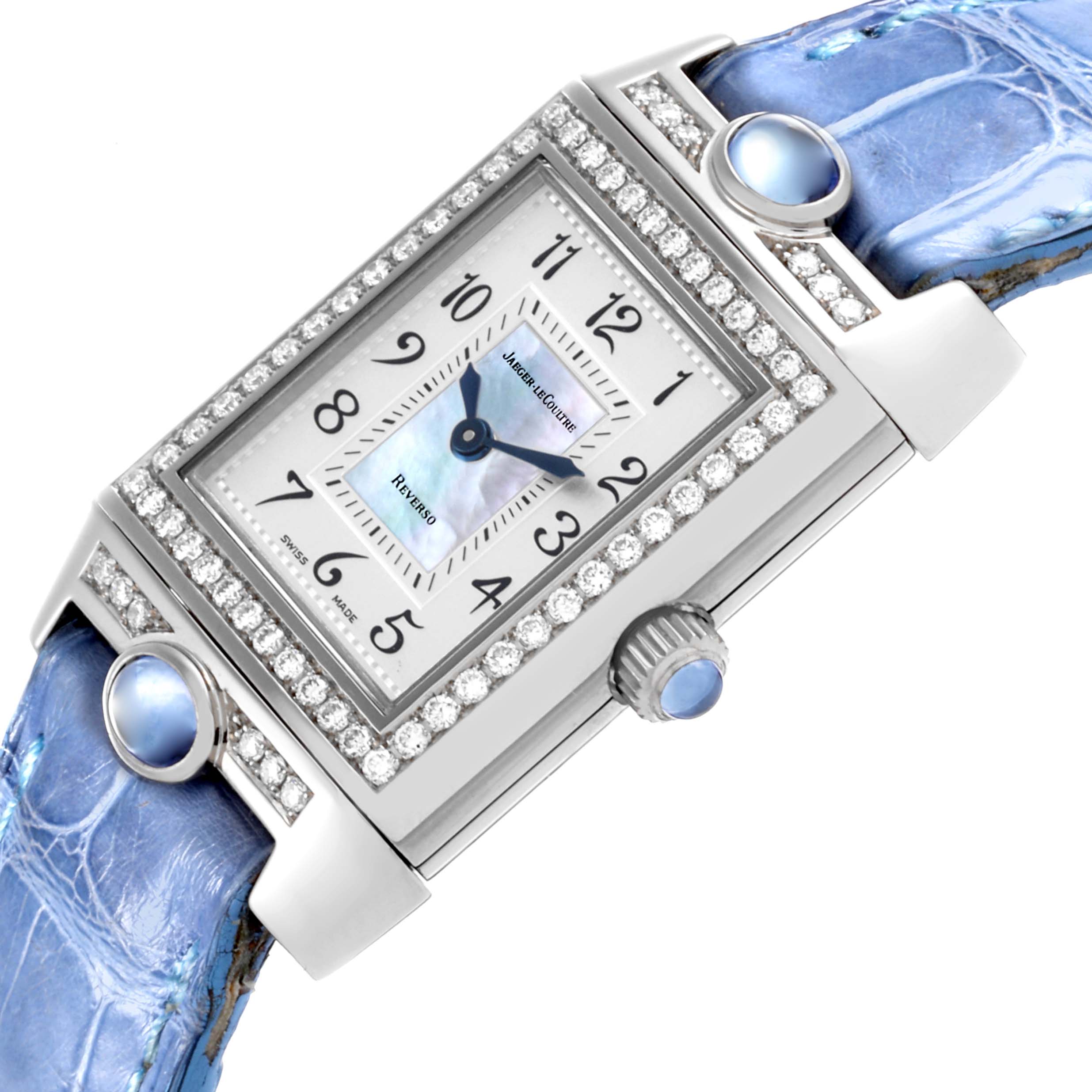 The Jaeger-LeCoultre Reverso watch is shown at an angled view, highlighting the face, crown, and blue strap with gem accents.