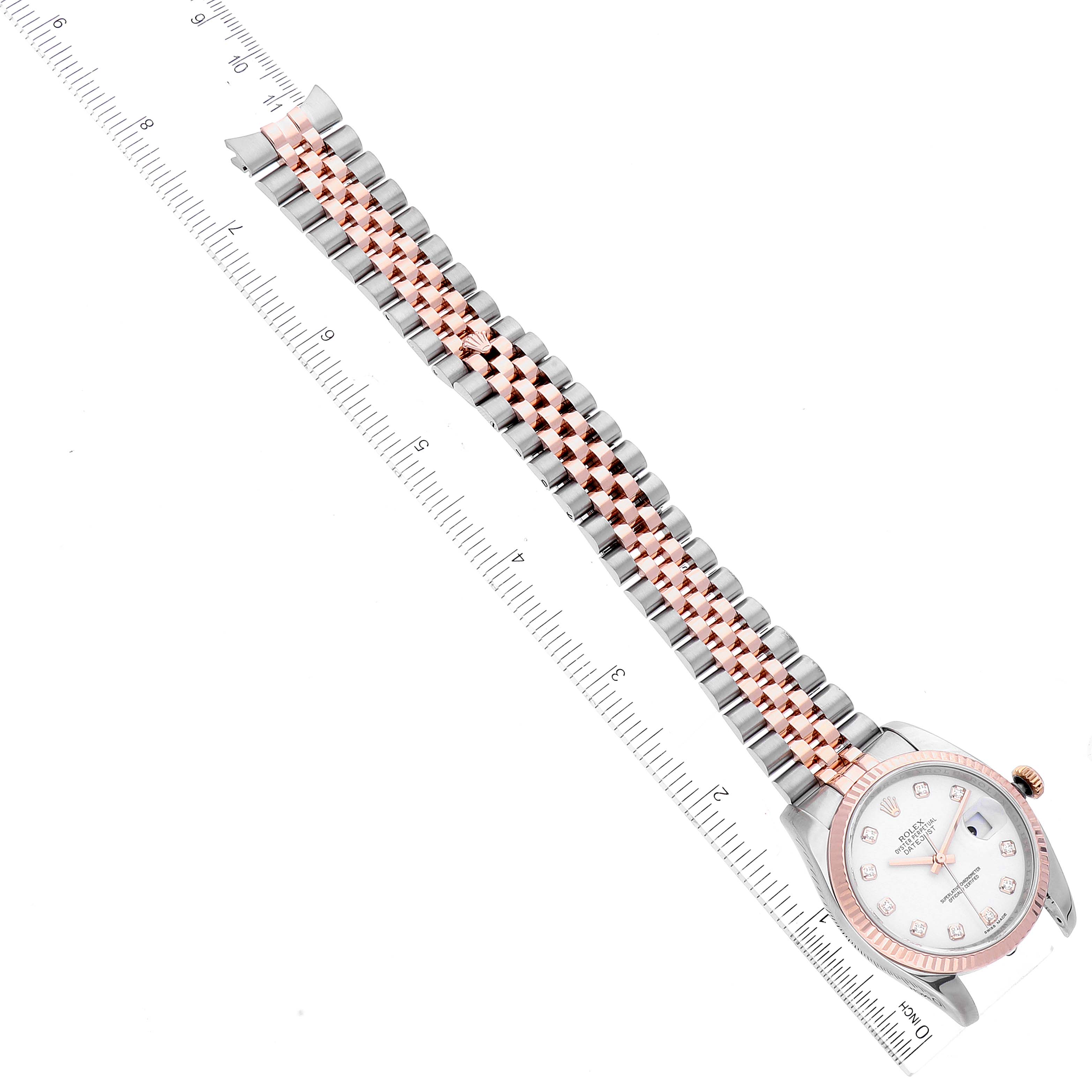 The image shows a top-down view of a Rolex Datejust 116231 Men's Steel and Gold (two tone) White Dial 116231 Men's Steel and Gold (two tone) White Dial watch, highlighting its face, bezel, and two-tone bracelet next to a ruler.