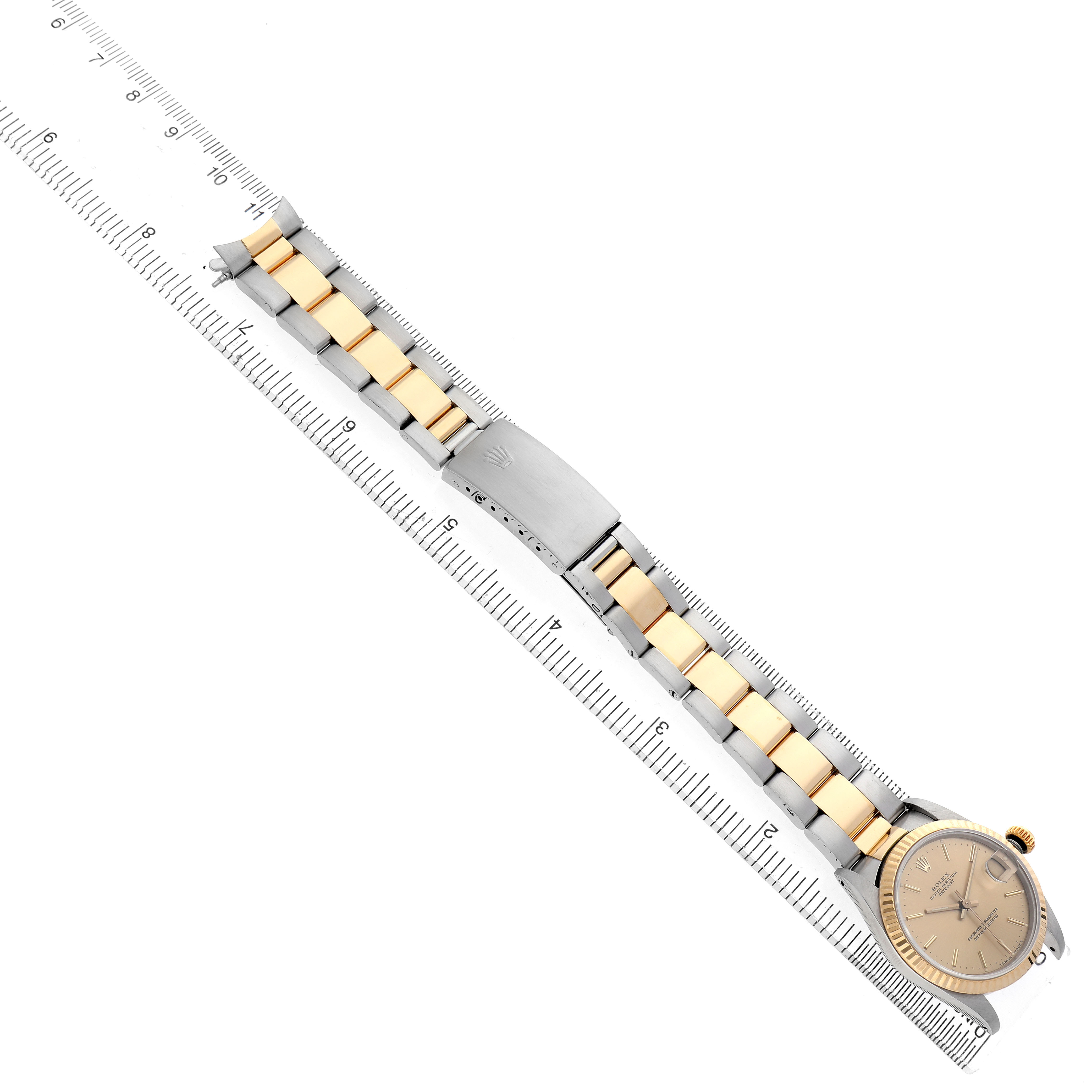 The image shows a Rolex Mid-Size 68273 Women's Steel and Gold (two tone) Champagne Dial watch from a top-down angle, highlighting the bracelet and face with a ruler beside it.