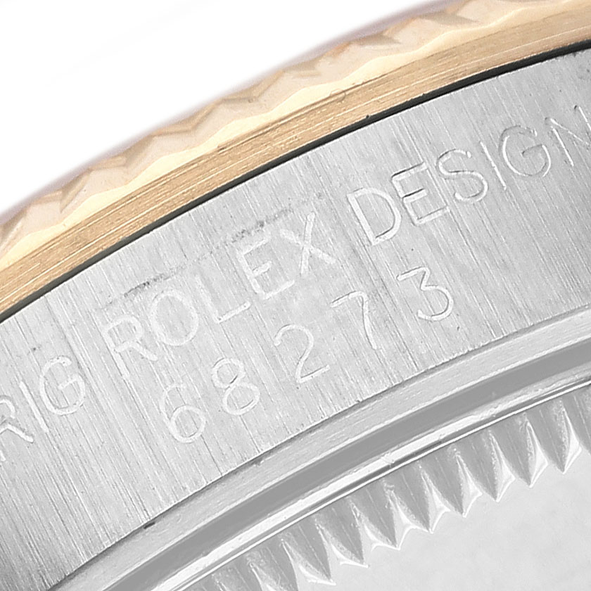 The image shows a close-up angle of the side edge and part of the bezel of a Rolex Mid-Size 68273 Women's Steel and Gold (two tone) Champagne Dial watch, highlighting engravings.