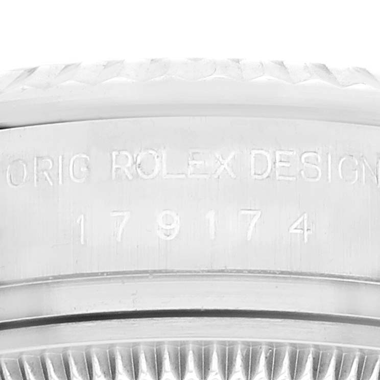 This image shows a close-up of the engraved serial number and fluted bezel of a Rolex Datejust 179174 Women's Stainless Steel Silver Dial 179174 Women's Stainless Steel Silver Dial watch.