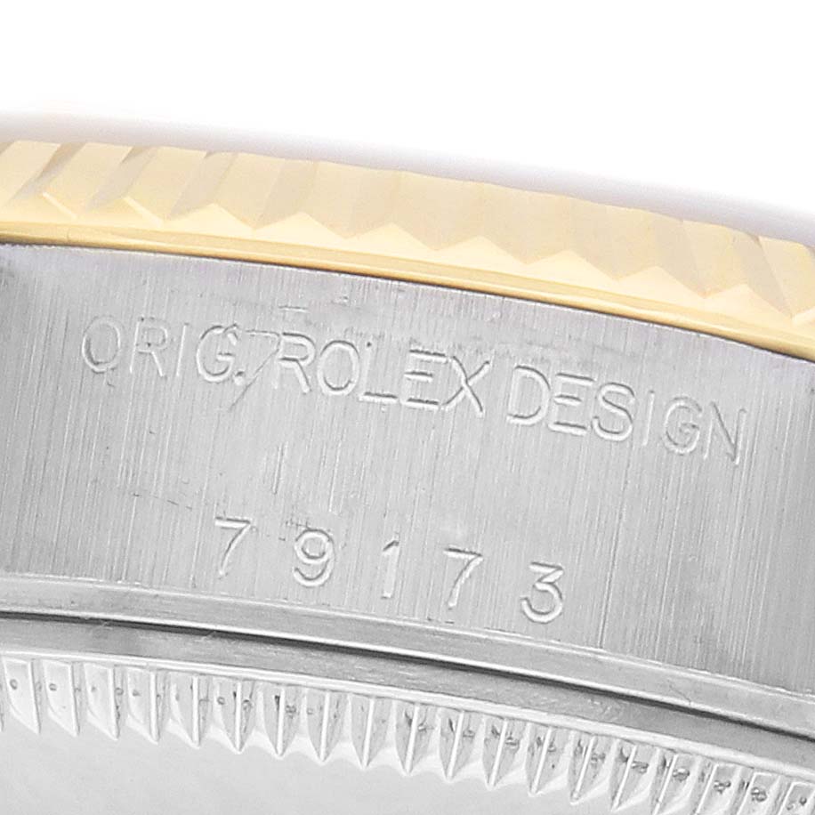 The image shows a close-up of the side of a Rolex Datejust 79173 Women
s Steel and Gold (two tone) Champagne Dial, featuring its engraved serial number and fluted bezel.