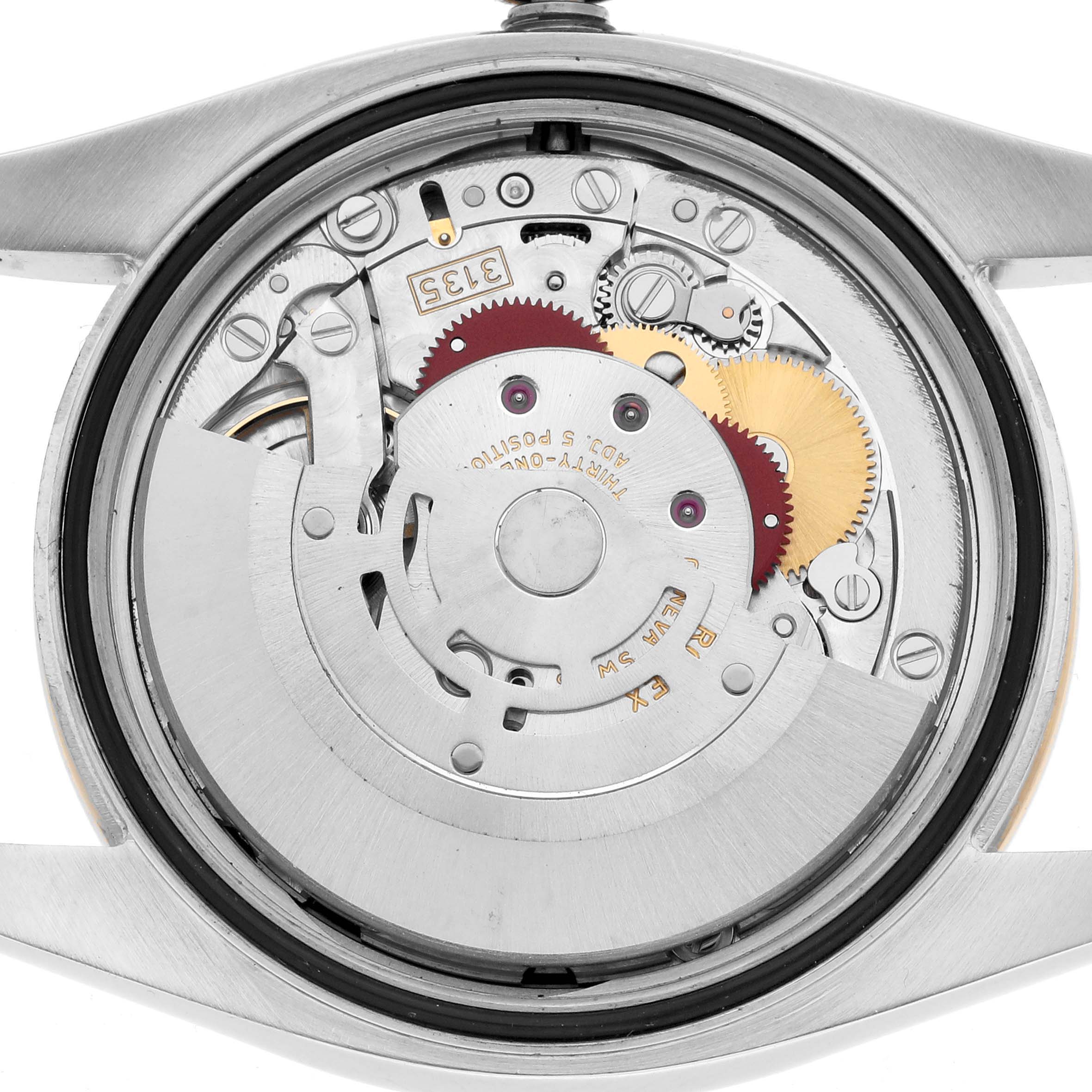 The image shows the movement and inner workings of a Rolex Datejust 116243 Men
s Steel and Gold (two tone) Black Dial watch from a rear angle, highlighting gears and components.