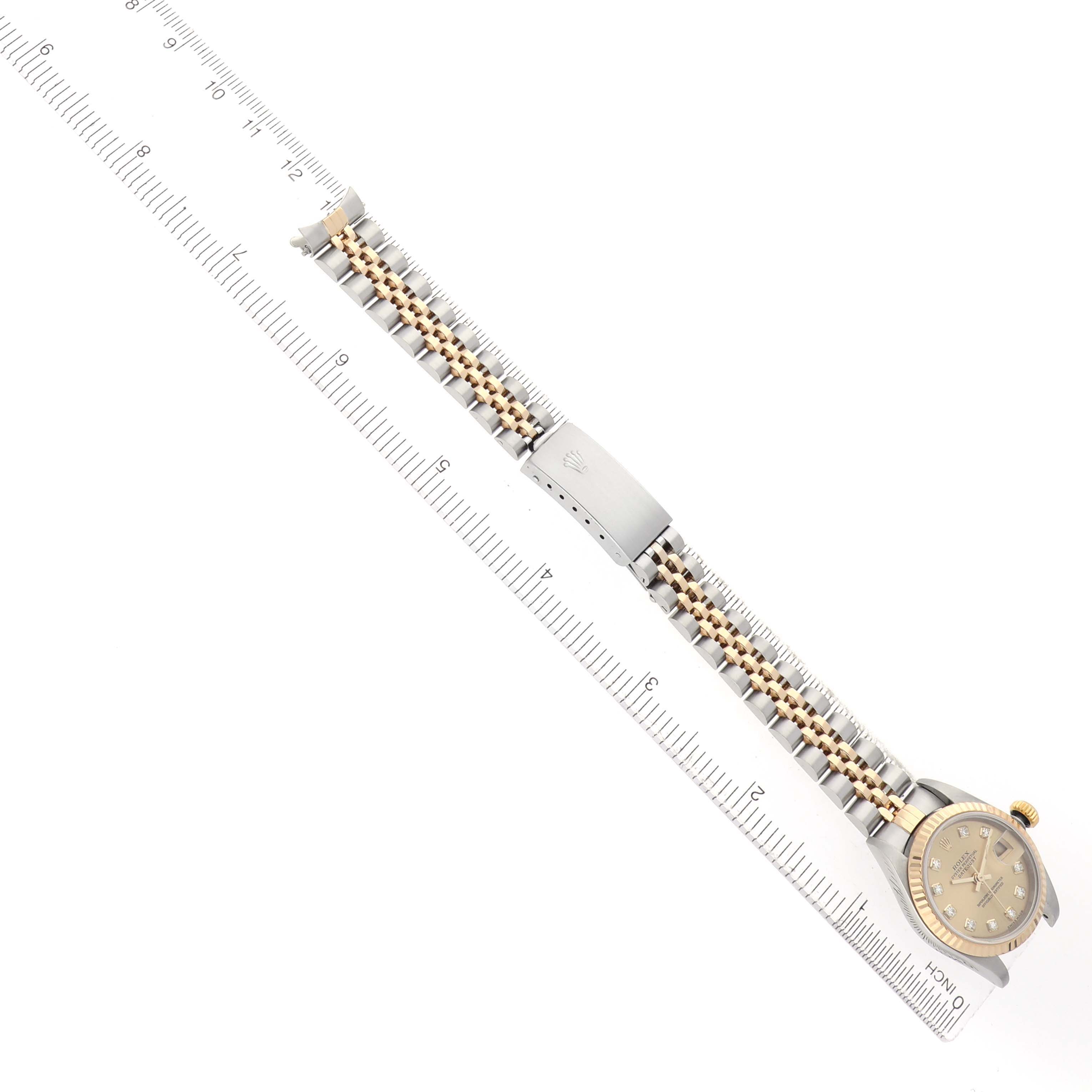 The Rolex Datejust 79173 Women
s Steel and Gold (two tone) Champagne Dial watch is shown from a top-down angle, revealing the entire bracelet, clasp, and face.