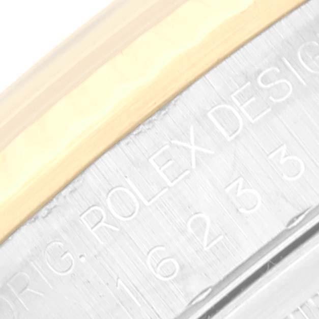This image shows an extreme close-up of the side engraving and metal bezel of a Rolex Datejust 16233 Men's Steel and Gold (two tone) Mother of Pearl Dial 16233 Men's Steel and Gold (two tone) Mother of Pearl Dial model watch.