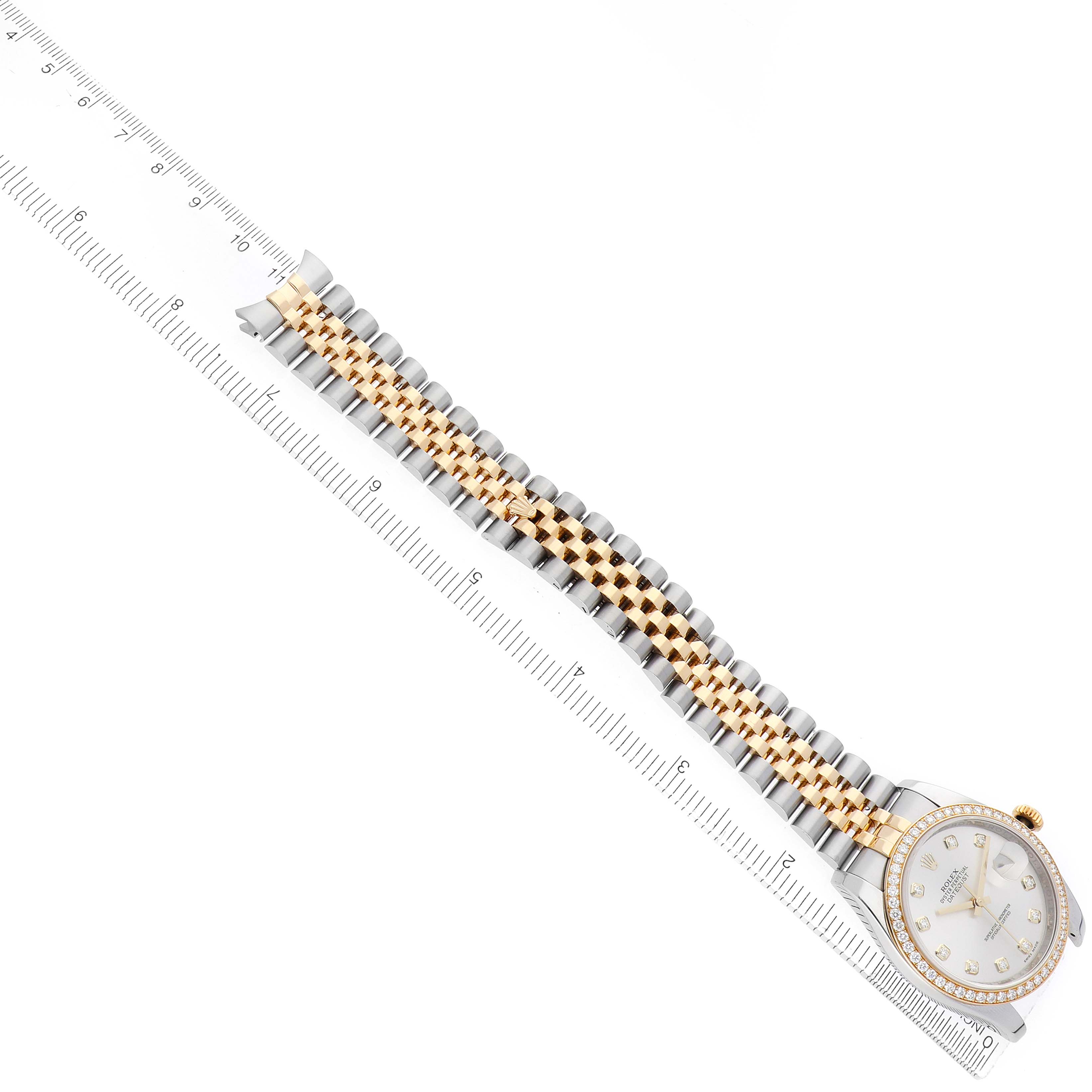 The image shows a Rolex Datejust 116243 Men
s Steel and Gold (two tone) Silver Dial watch from a top view, highlighting its two-tone bracelet and bezel alongside a ruler.