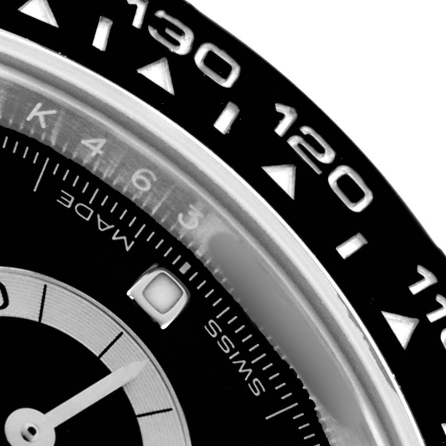 The image shows a close-up of the bezel and part of the dial of a Rolex Daytona 116500 Men
s Stainless Steel Black Dial, featuring the tachymetric scale.