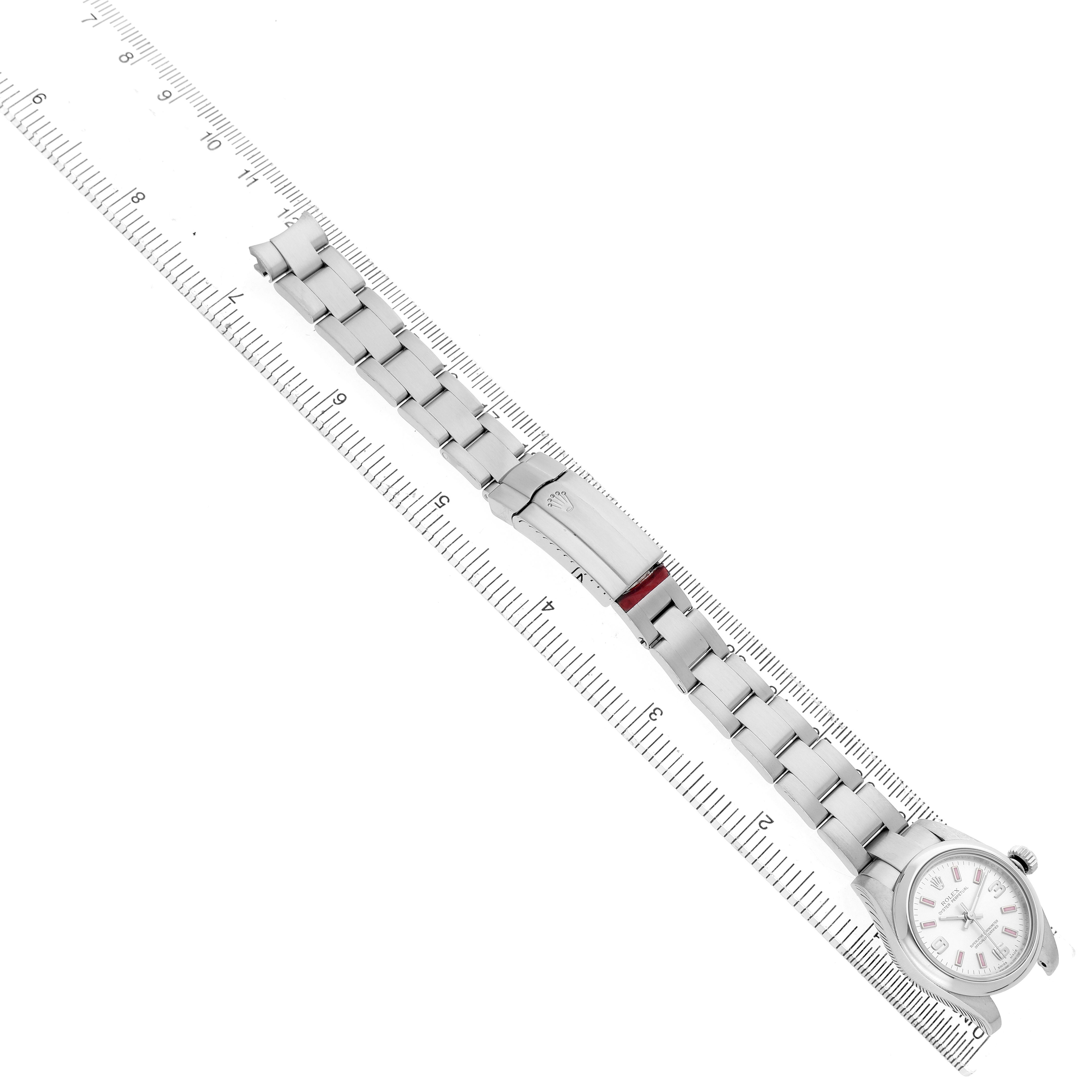 The Rolex Oyster Perpetual 176200 Women's Stainless Steel Silver Dial watch is shown from the top, highlighting the face, bracelet, and clasp laid out alongside a ruler.