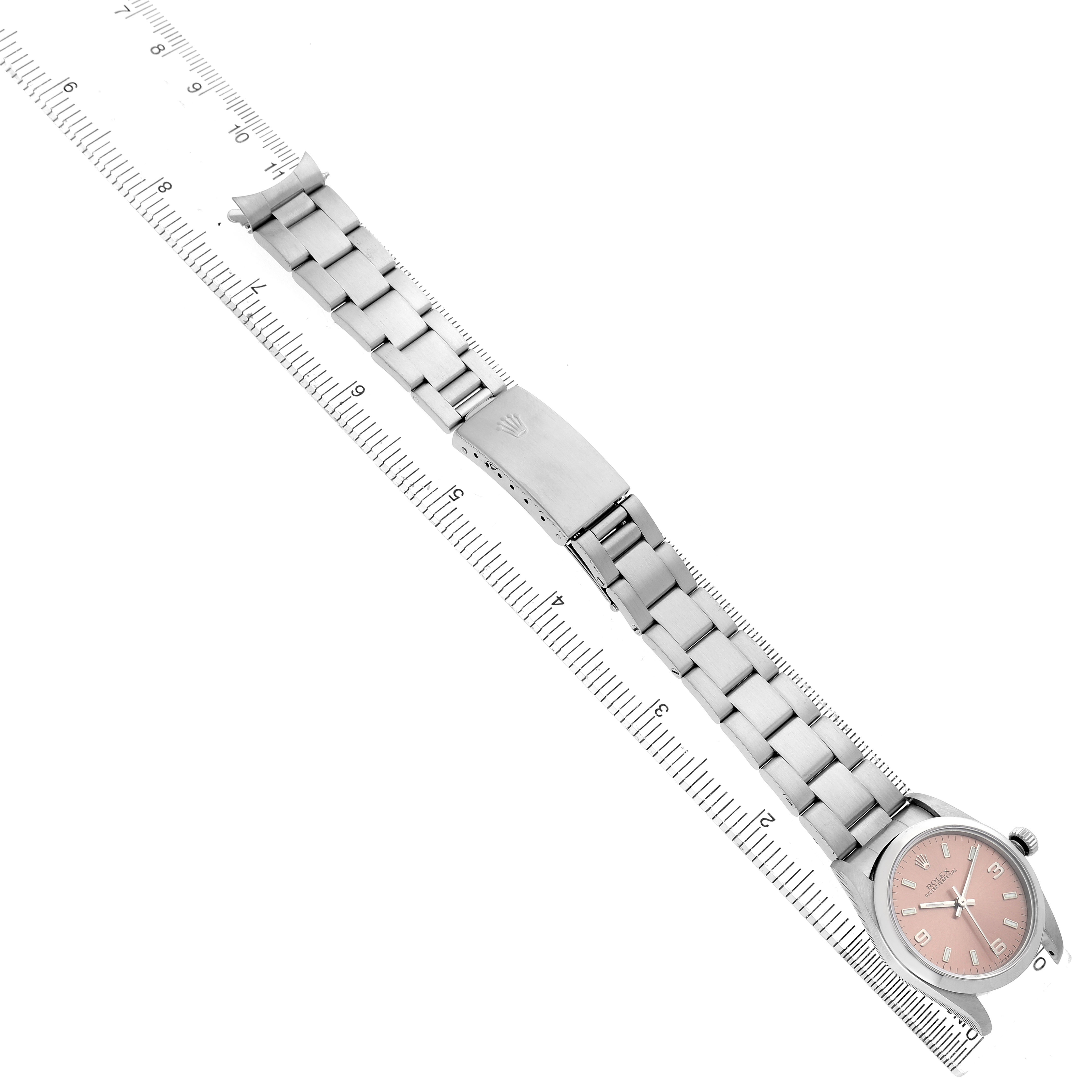 The image shows a Rolex Mid-Size 77080 Women's Stainless Steel Pink Dial watch laid flat with its bracelet extended alongside a ruler.